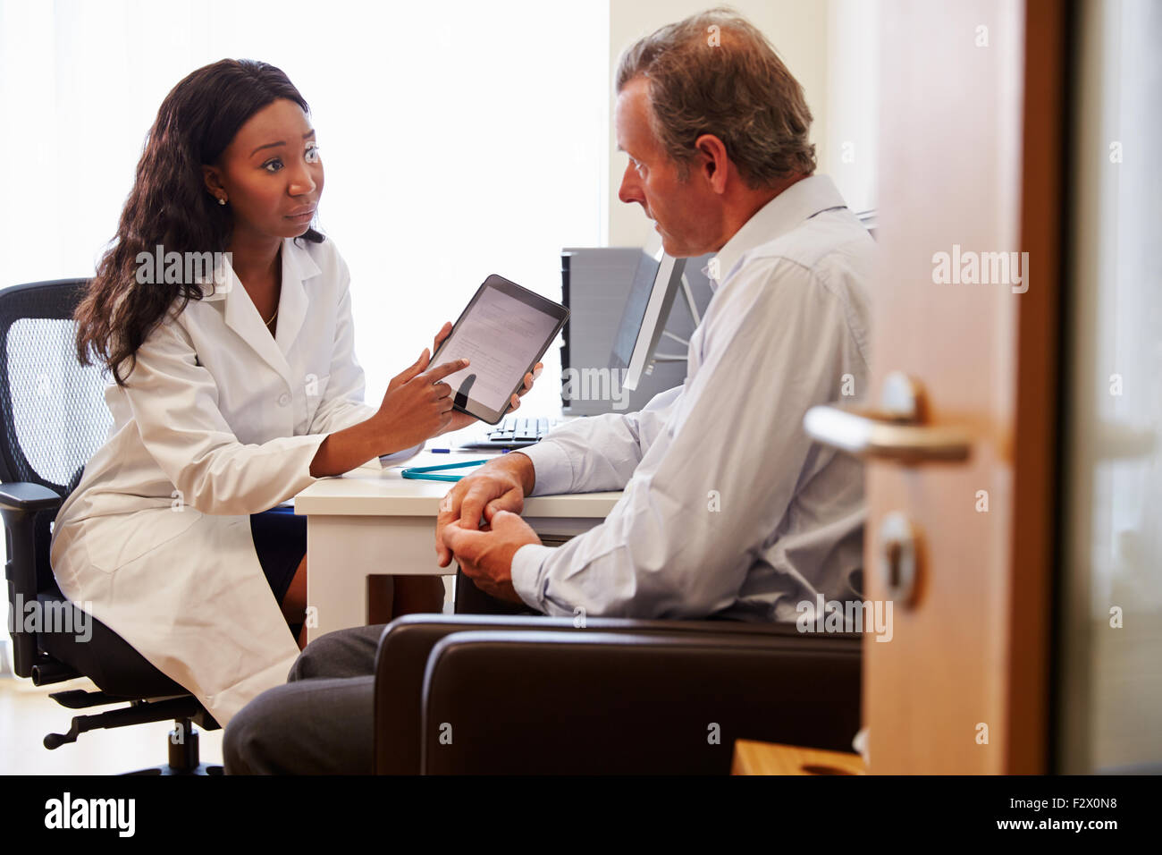 Paziente avente la consultazione con il medico donna in Office Foto Stock
