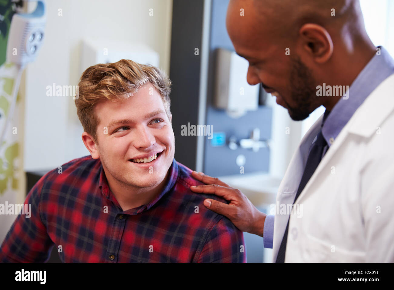 Paziente di sesso maschile di essere rassicurati dal medico nella stanza di ospedale Foto Stock