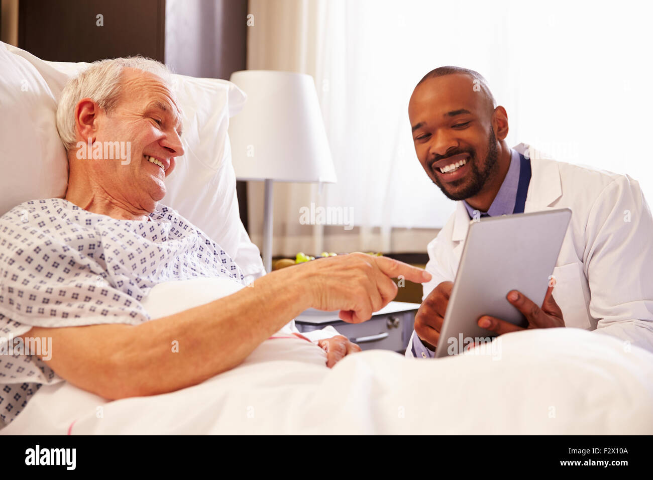 Medico parlando a Senior paziente di sesso maschile nel letto di ospedale Foto Stock