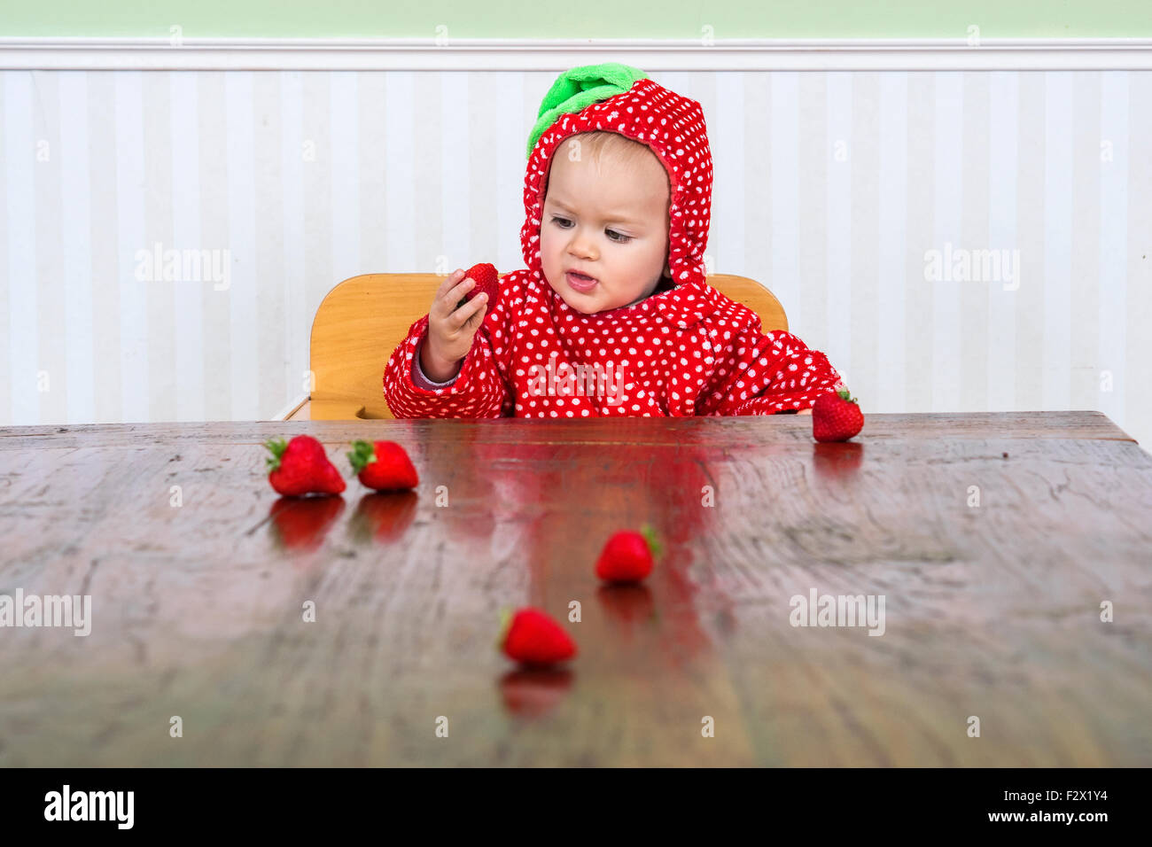 Carino bambino in tuta di bacche di mangiare fragole Foto Stock