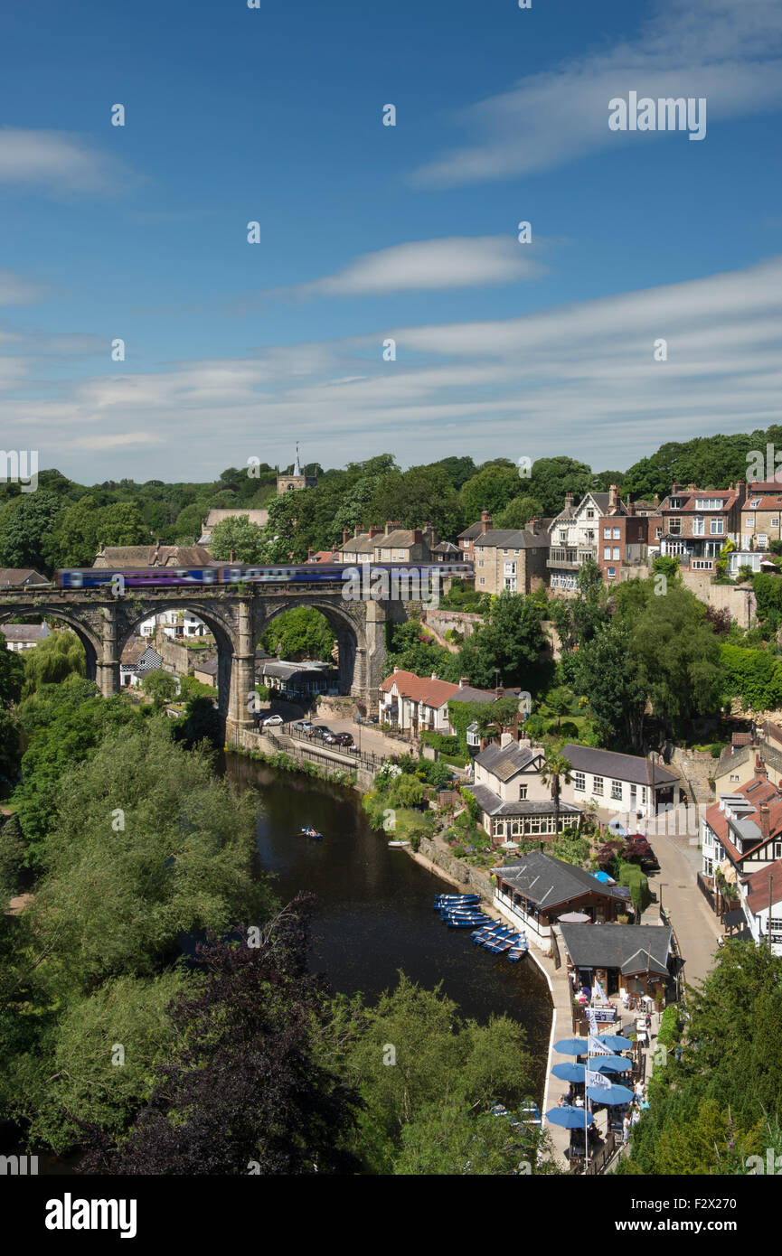 Cielo blu sopra Knaresborough, England, Regno Unito - scenic estiva soleggiata vista del treno sul viadotto del ponte, sul fiume Nidd, barche, gola boscosa & riverside case. Foto Stock