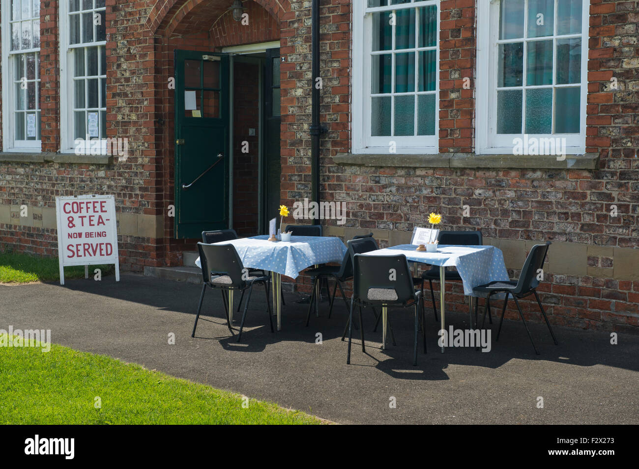 Sedie e tavoli (con un panno) istituito al di fuori Poppleton superiore village hall dove bevande vengono serviti - nessun cliente come ancora. Vicino a York, GB, UK. Foto Stock