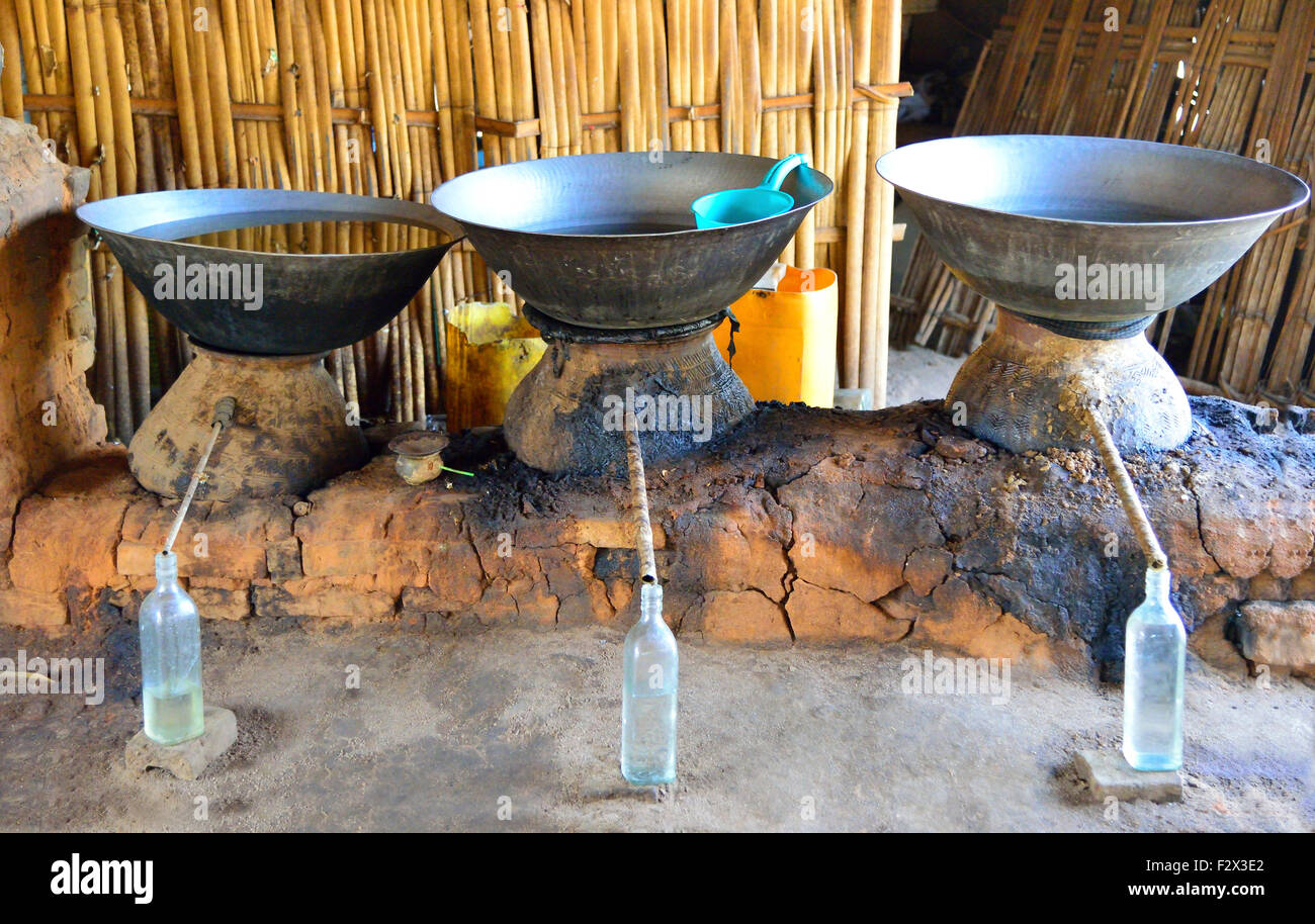 Una distilleria rurali rendendo il vino di riso. La distillazione avviene in fuoco riscaldata alambicchi di terracotta e alcool raccoglie in bottiglie. Nel nord del Myanmar (Birmania) Foto Stock