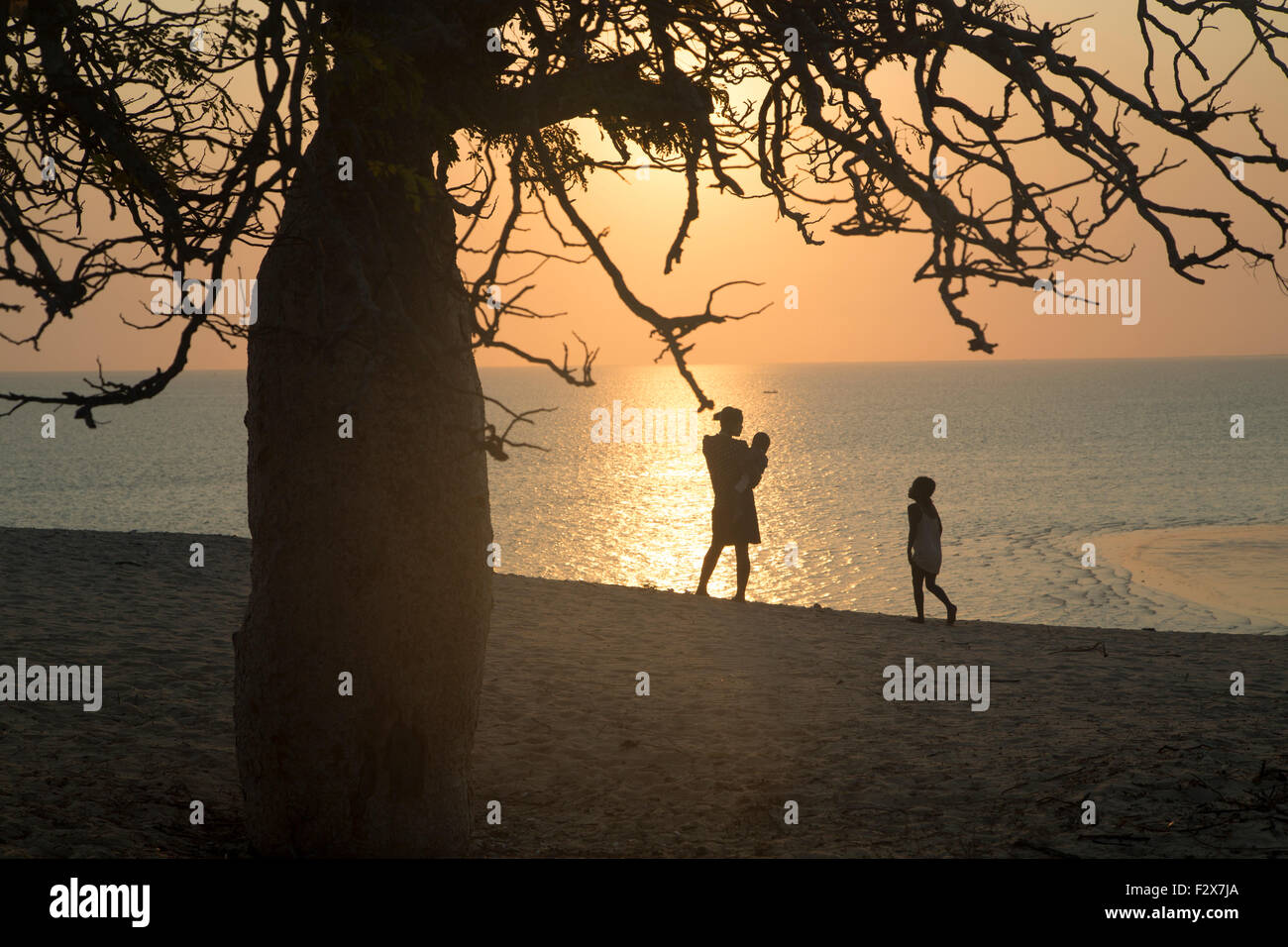 Africa e Madagascar, Donna con bambini in piedi al mare al tramonto Foto Stock