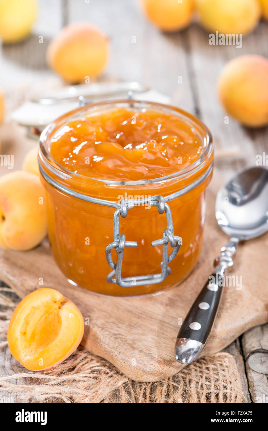 Un vasetto di marmellata di albicocche (close-up shot) con un po' di frutta fresca Foto Stock