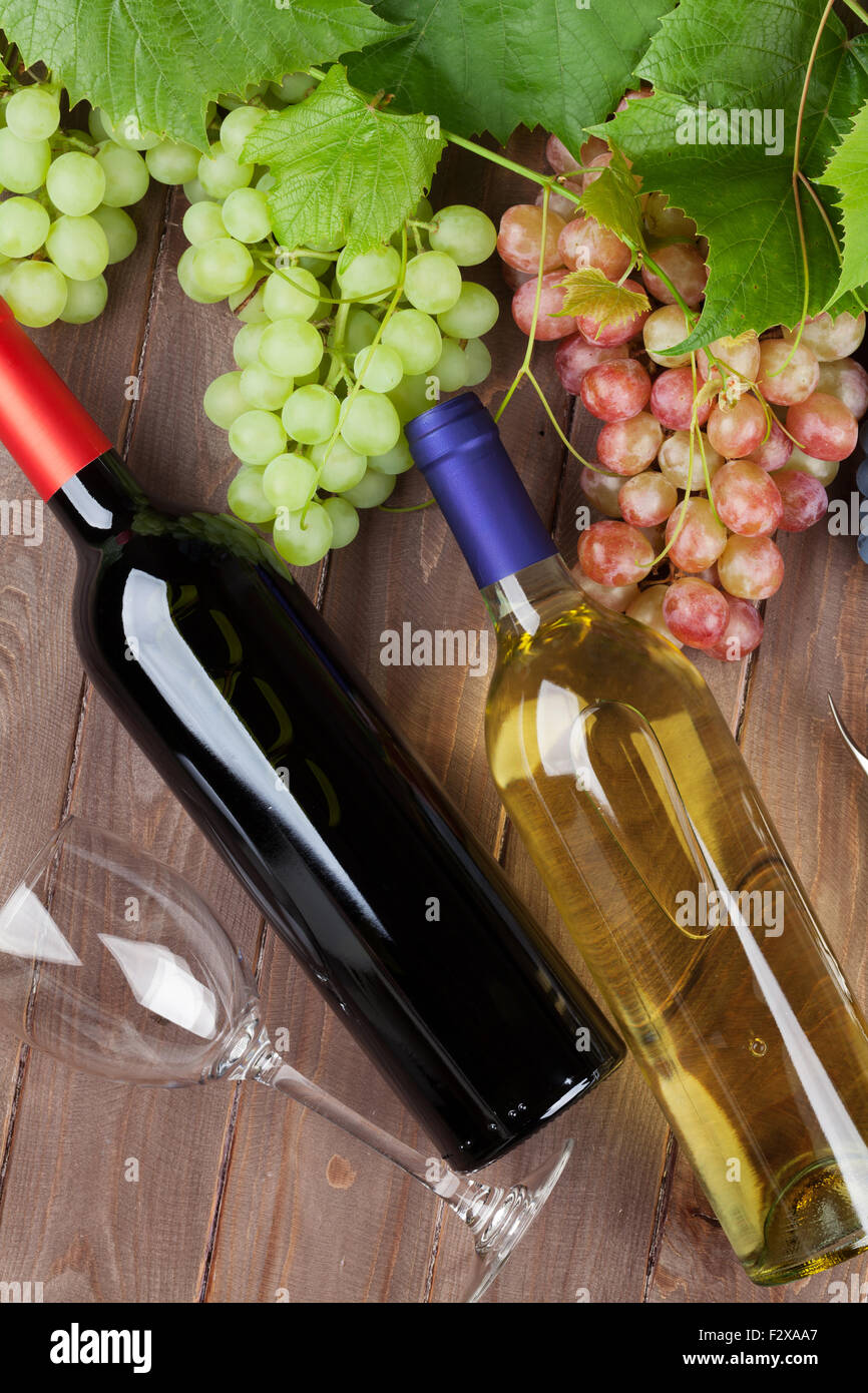 Vino bianco e rosso bottiglie, vigna e del grappolo di uva sul tavolo da giardino Foto Stock