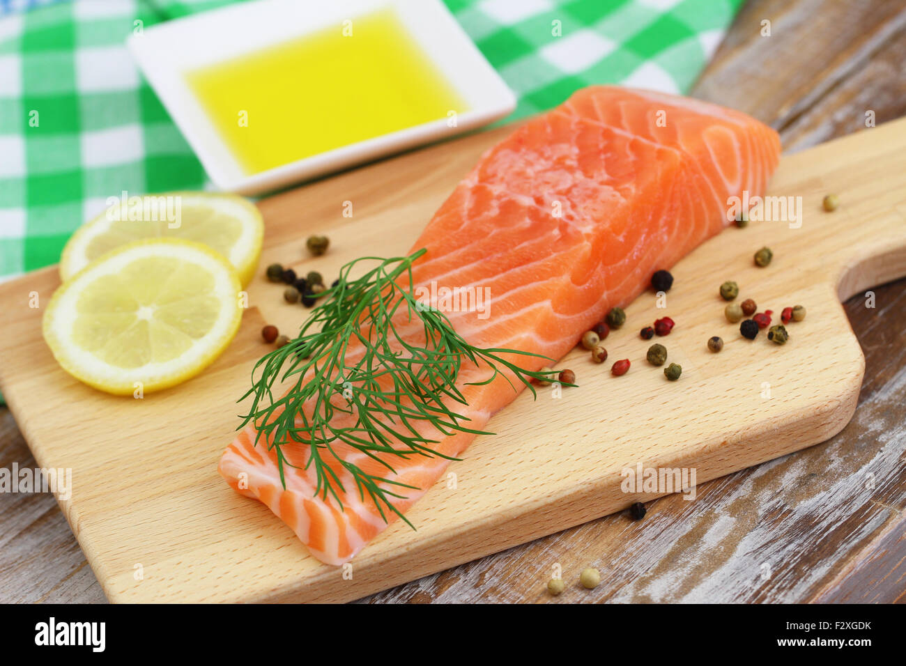 Raw bistecca di salmone su tavola di legno con limone e pepe e olio di oliva Foto Stock