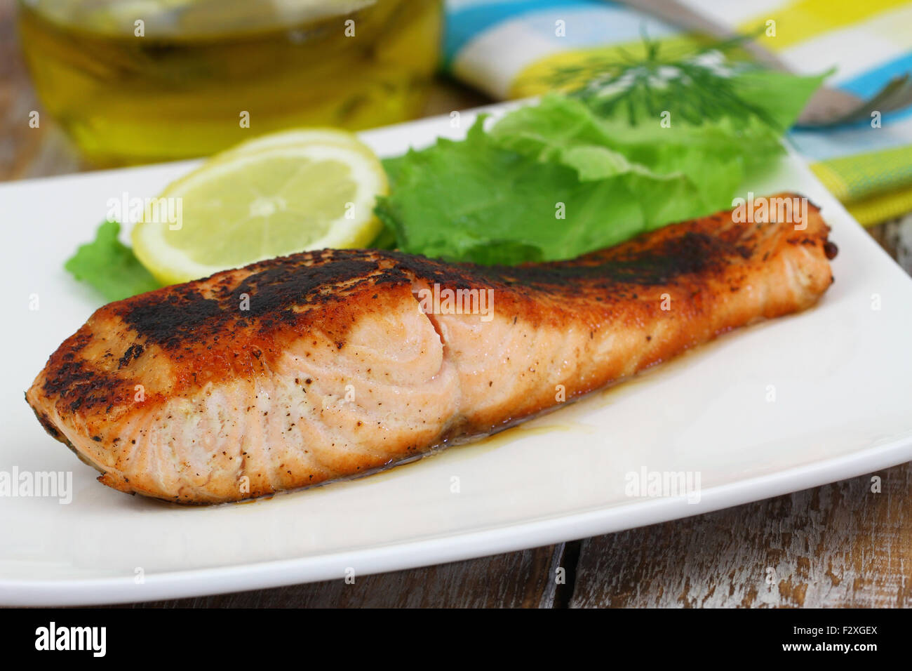 Salmone alla griglia sulla piastra bianca con insalata di contorno e limone Foto Stock