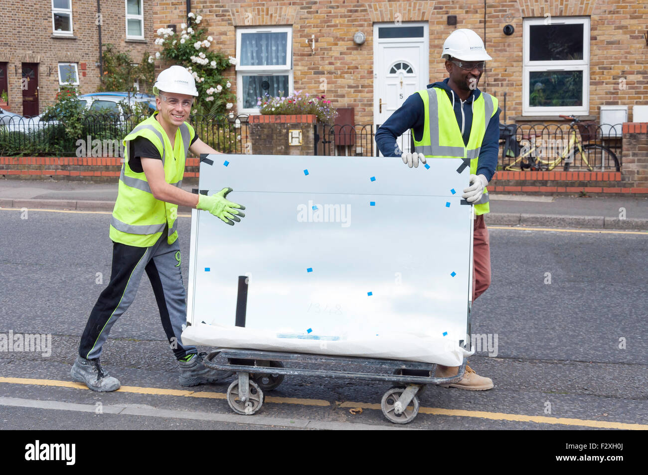 Lavoratori edili il trasporto di lastre di vetro, Green Dragon Lane, Brentford, Greater London, England, Regno Unito Foto Stock