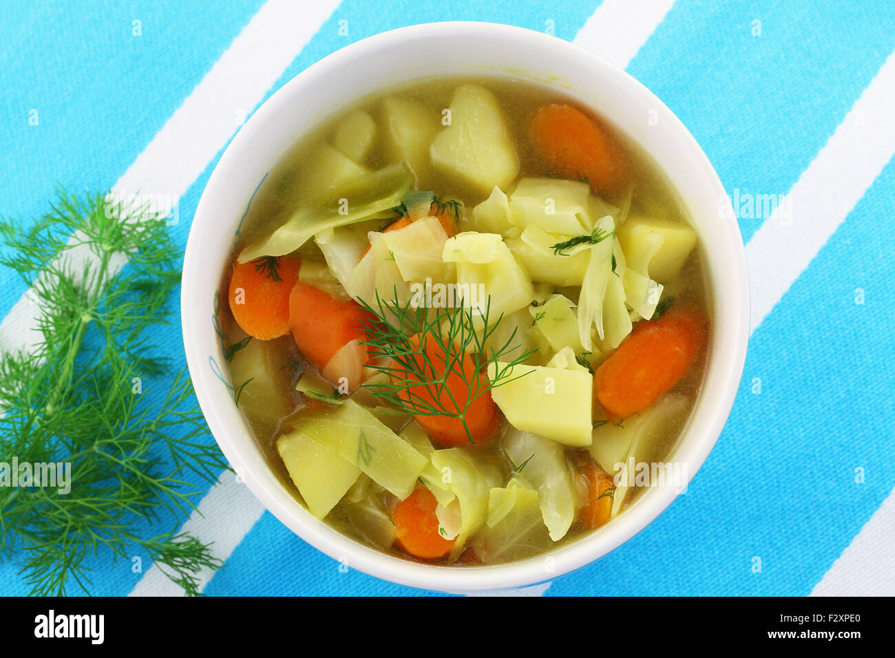 Ciotola di zuppa di cavolo con aneto fresco striata sul panno da cucina Foto Stock