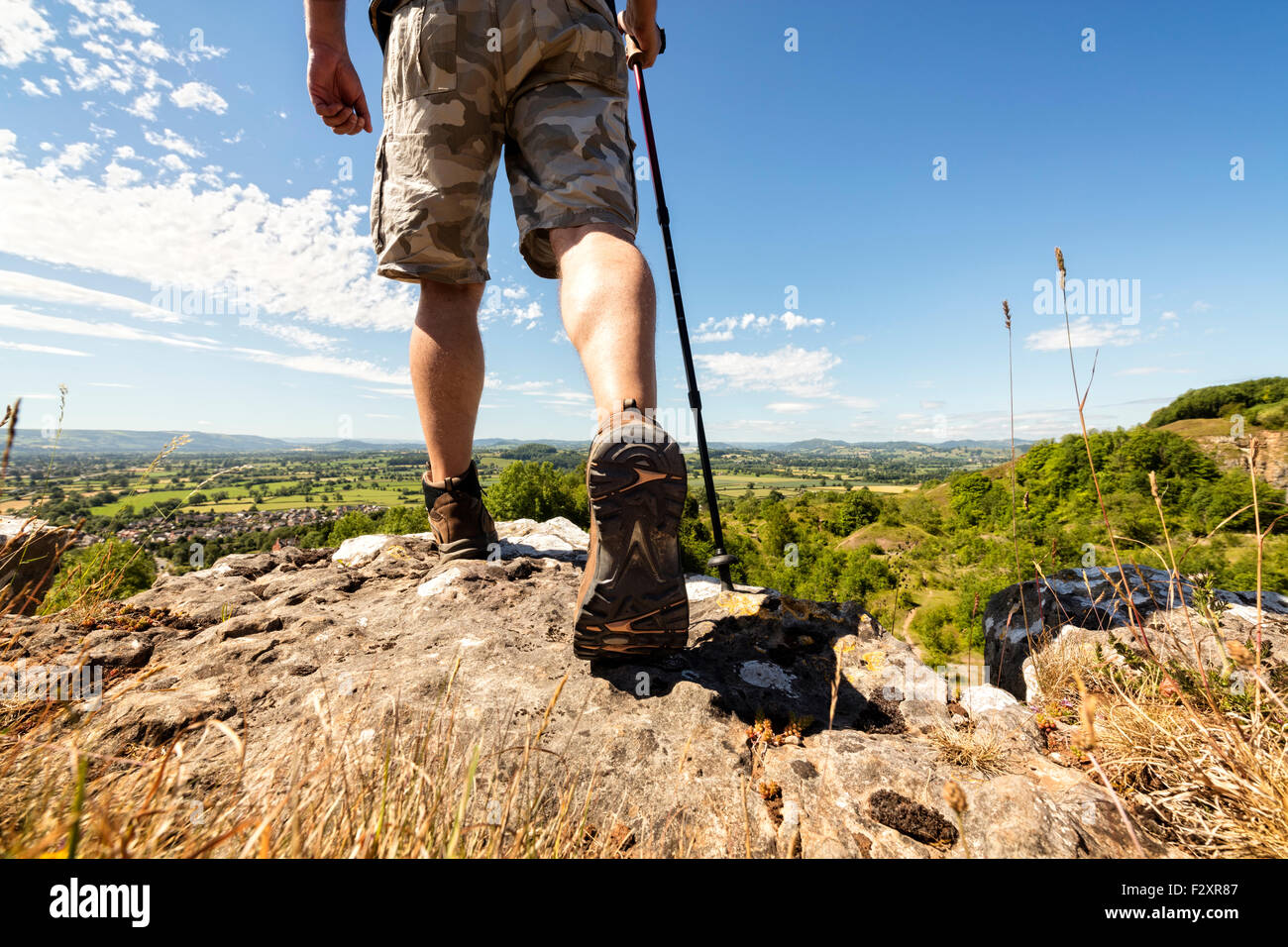 Escursionista escursionismo su un sentiero di montagna con panorami distanti di campagna in estate sole Foto Stock