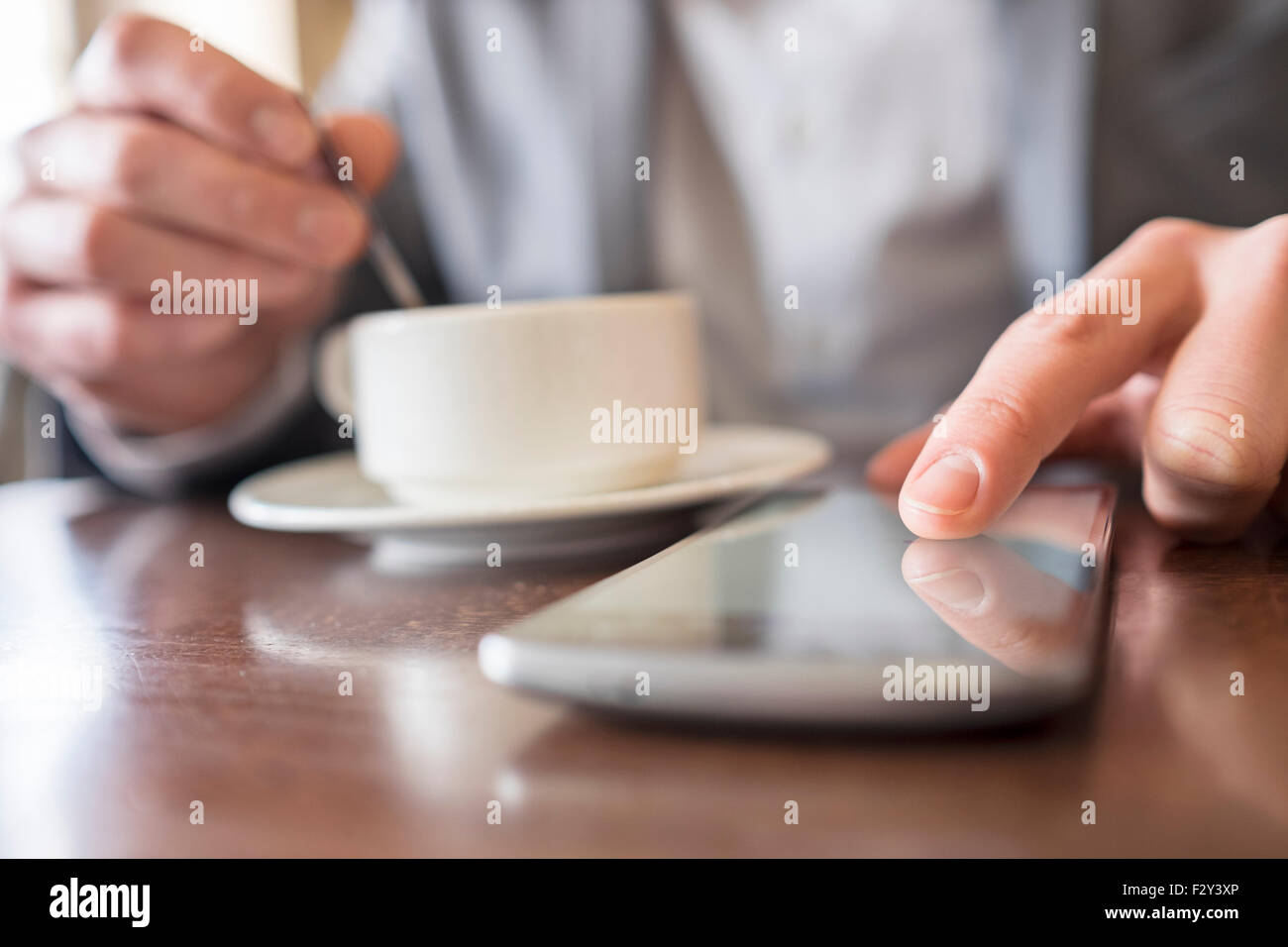 Close-up uomo mani usando il cellulare in coffee bar Foto Stock