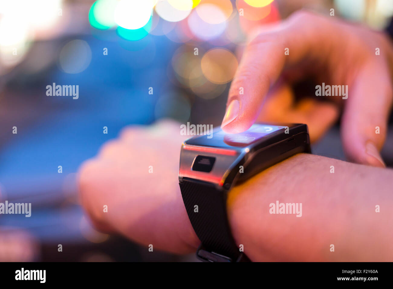Uomo che utilizza la sua smart watch app in strada di notte di luce sullo sfondo bokeh. close up di mani maschio Foto Stock