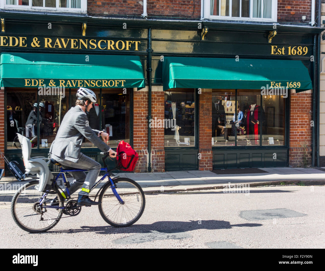 Ciclista di fronte Ede e Ravenscroft negozio di abbigliamento, Cambridge, Inghilterra, Regno Unito Foto Stock