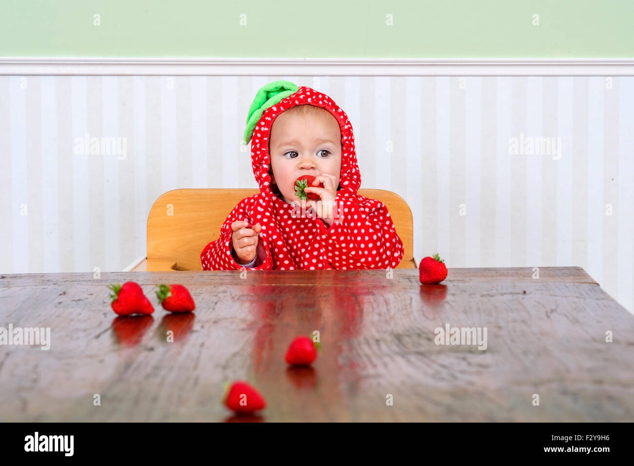Adorable baby in una bacca suit mangiare fragole Foto Stock