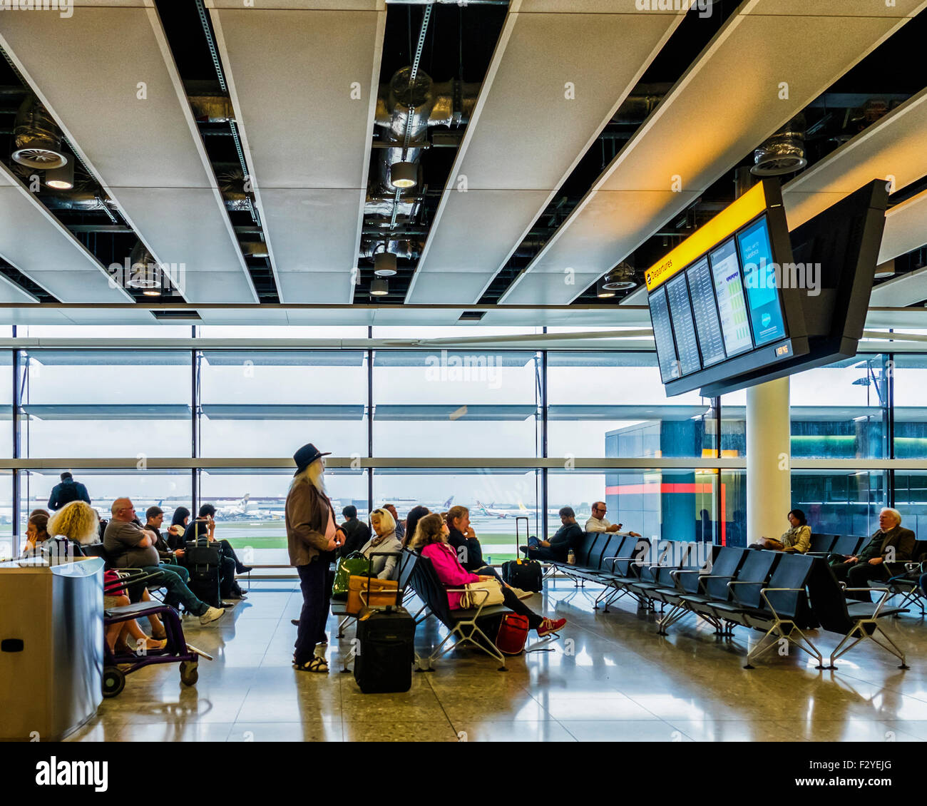 Dall'Aeroporto Londra Heathrow Terminal 2, Queen Elizabeth il terminale T2, i passeggeri di attendere nella sala partenze Foto Stock