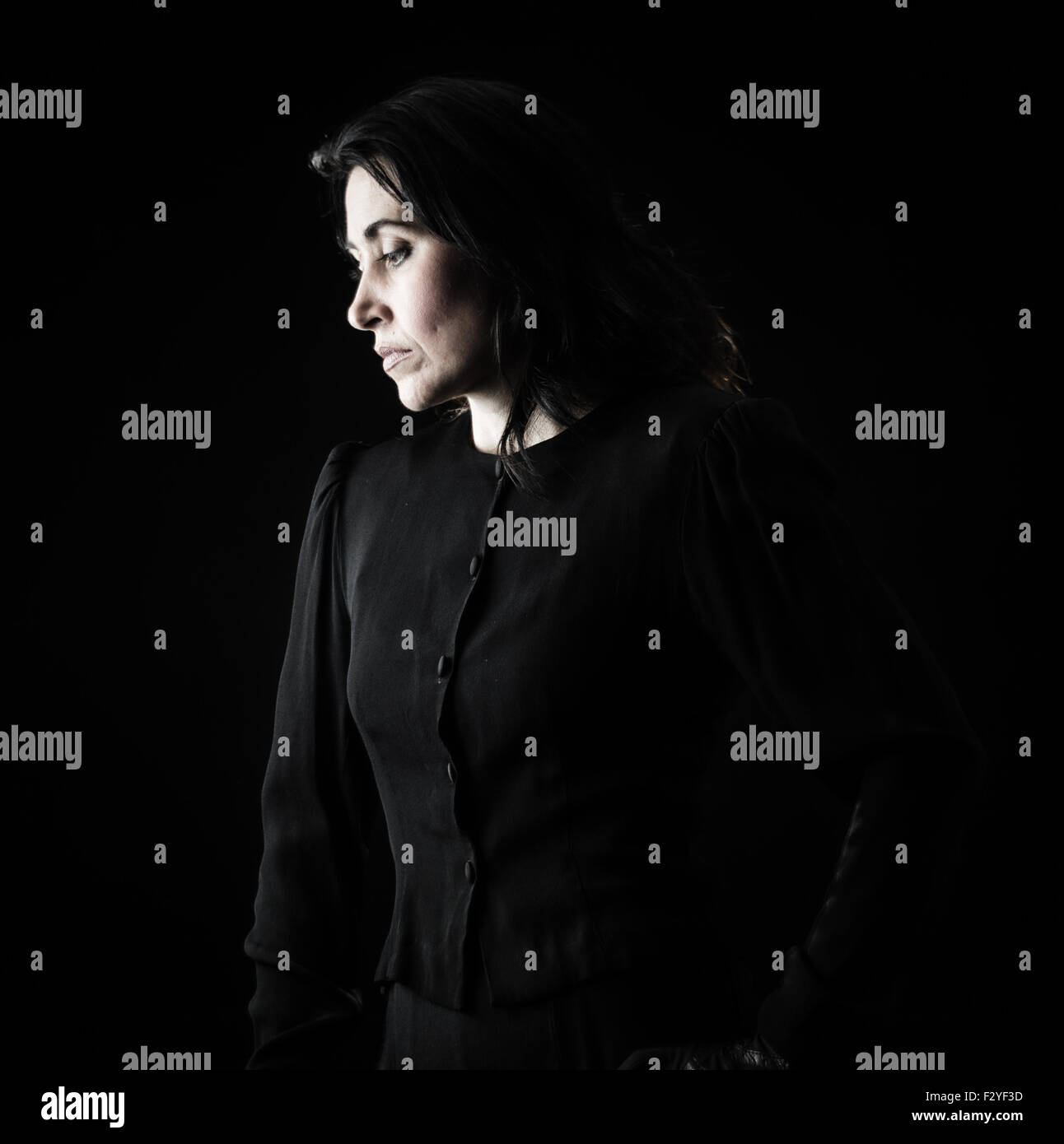 Brunette donna in nero cercando triste, serio, pensieroso Foto Stock