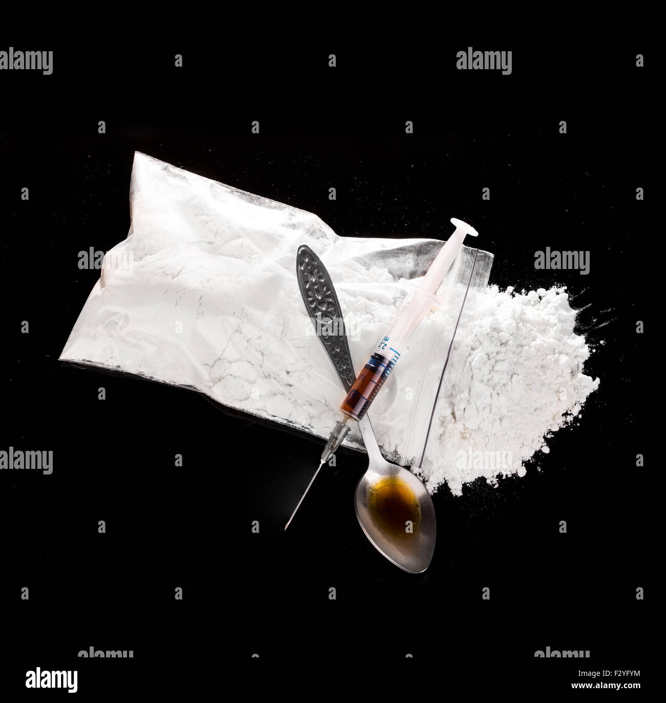 La polvere del farmaco, il farmaco siringa e cotti del farmaco su cucchiaio close-up su uno sfondo nero. Foto Stock