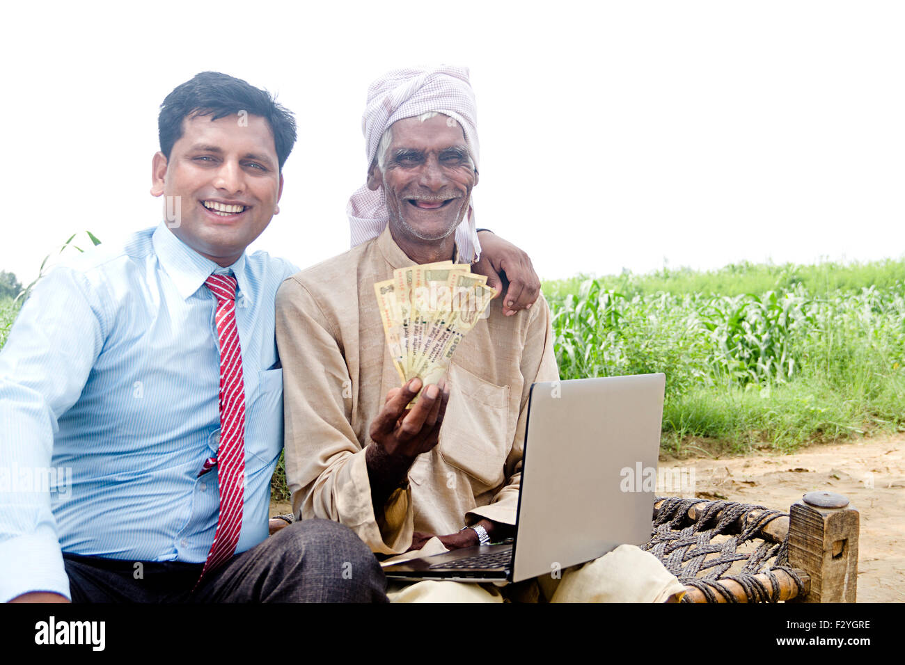 Rurale indiano Business Man e agricoltore farm laptop e il denaro che mostra Foto Stock