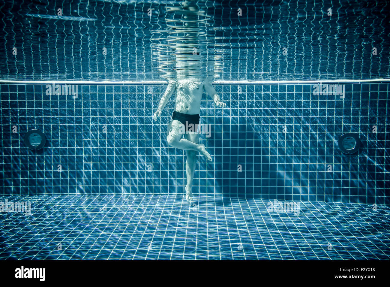 Uomo in piedi sotto acqua in una piscina Foto Stock