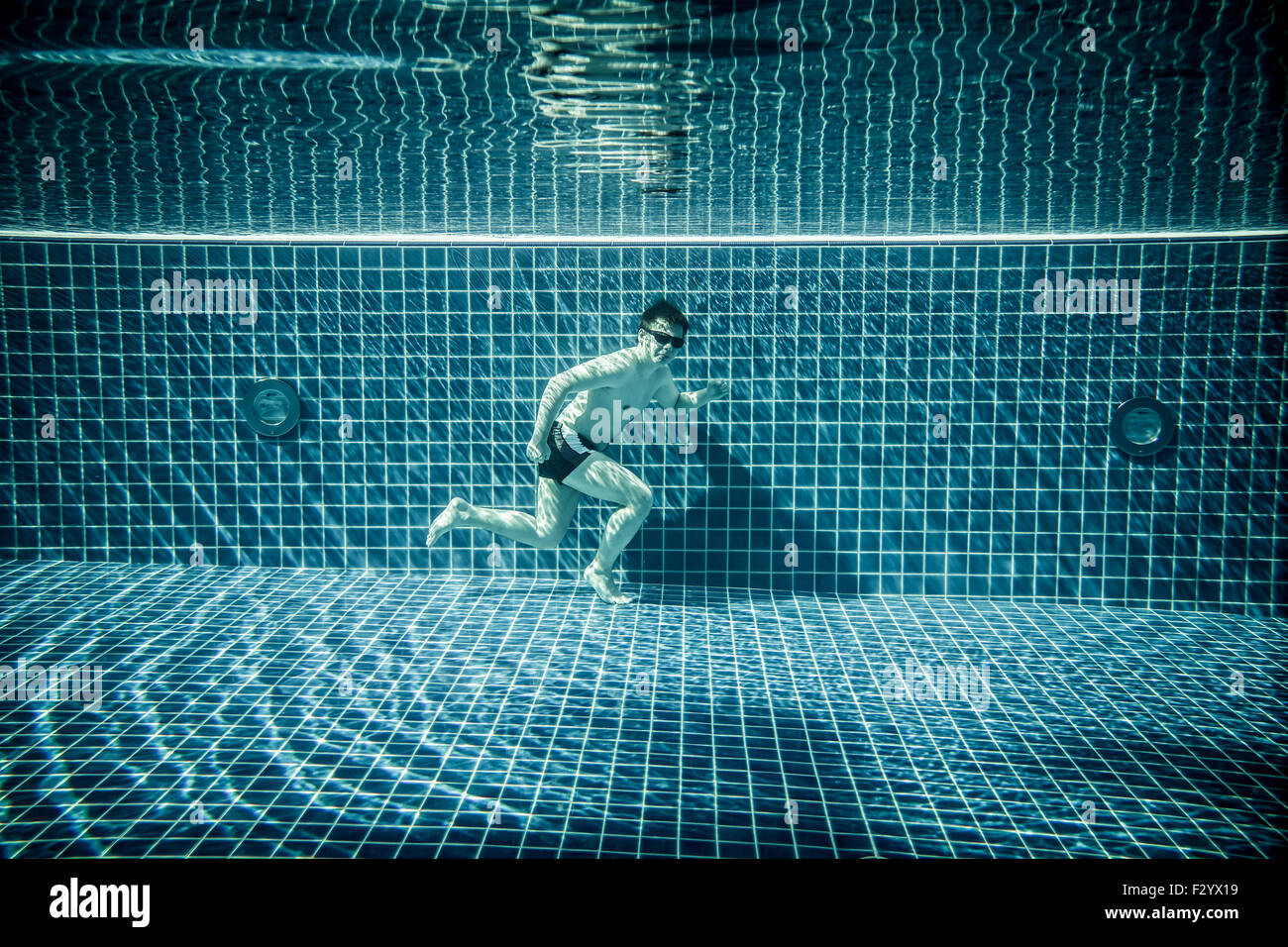 L'uomo sotto l'acqua scorre lungo il fondo di una piscina Foto Stock