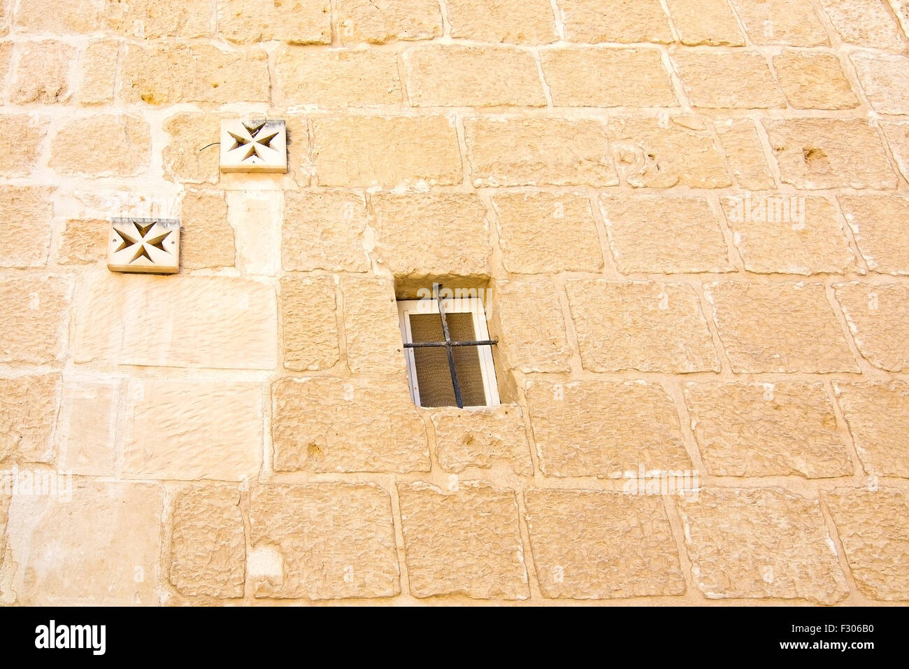 Croce di Malta decorazioni murali e finestra sul vecchio muro di Mdina, Malta. Foto Stock