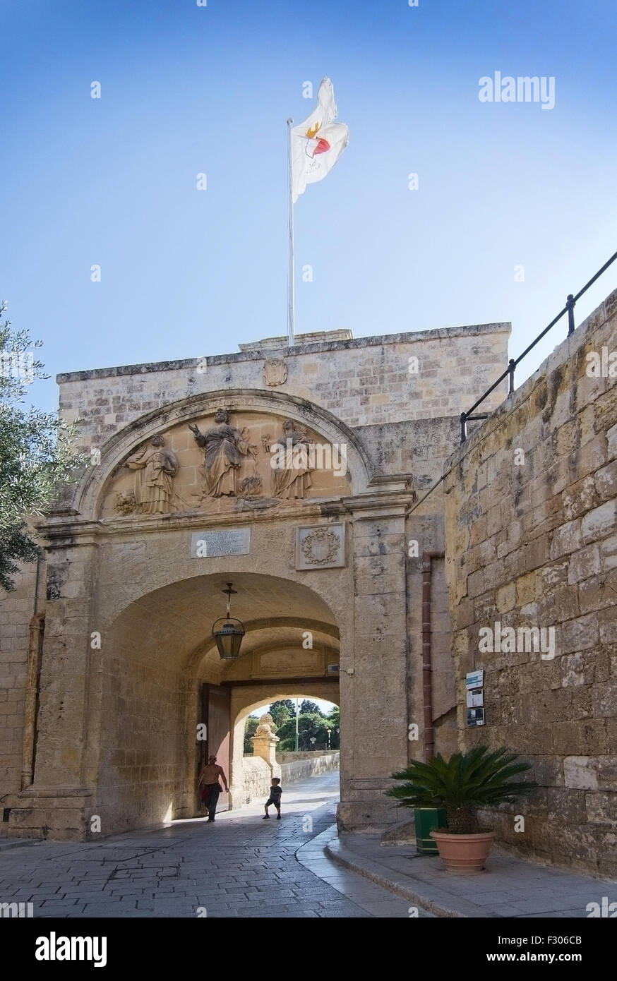 Uomo e ragazzo che entra attraverso l'ingresso ad arco il portale per la città silenziosa Mdina in una giornata di sole in settembre, Malta. Foto Stock