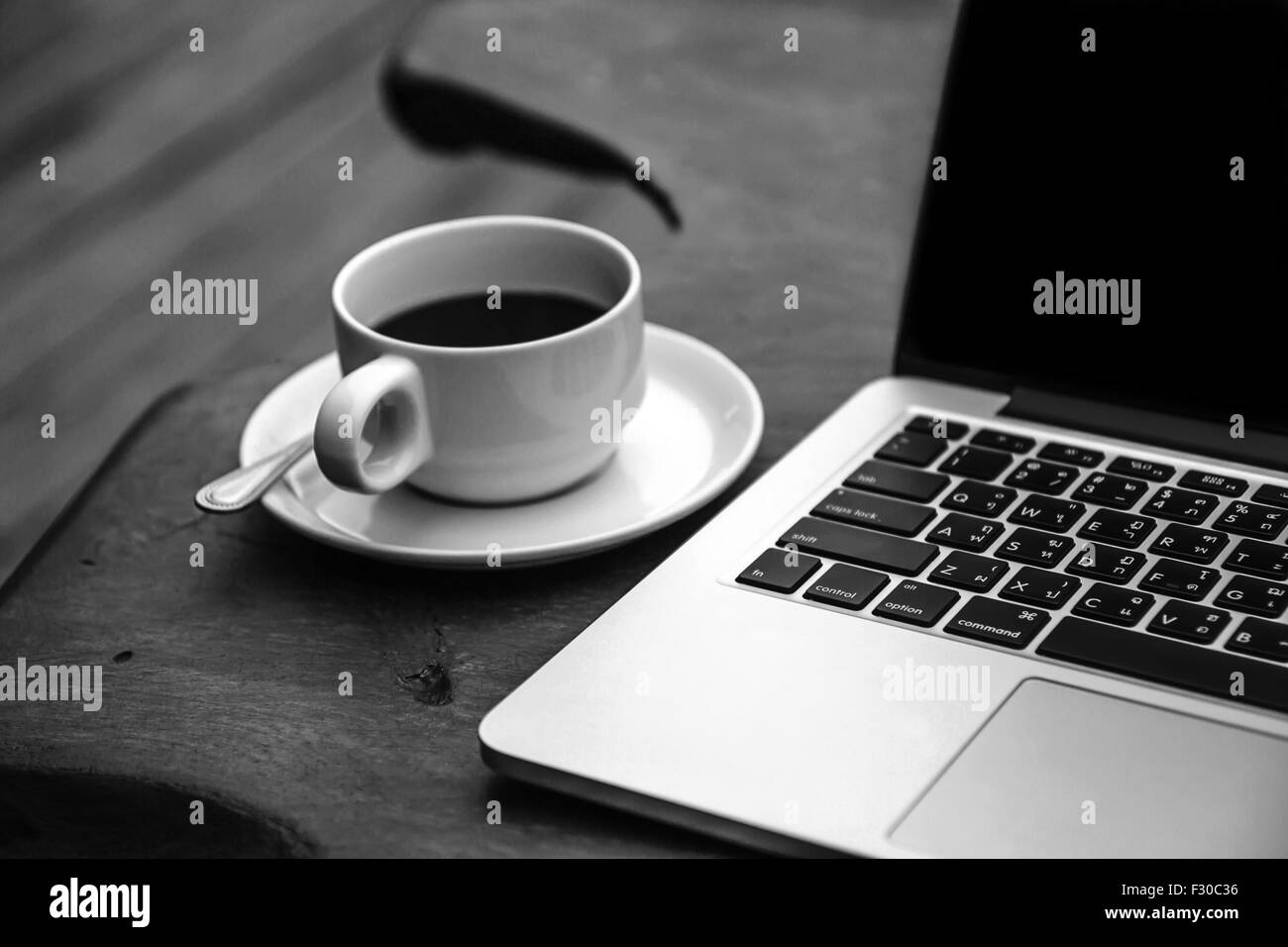 Nero caffè in una tazza bianca su una tabella con un computer. Foto Stock