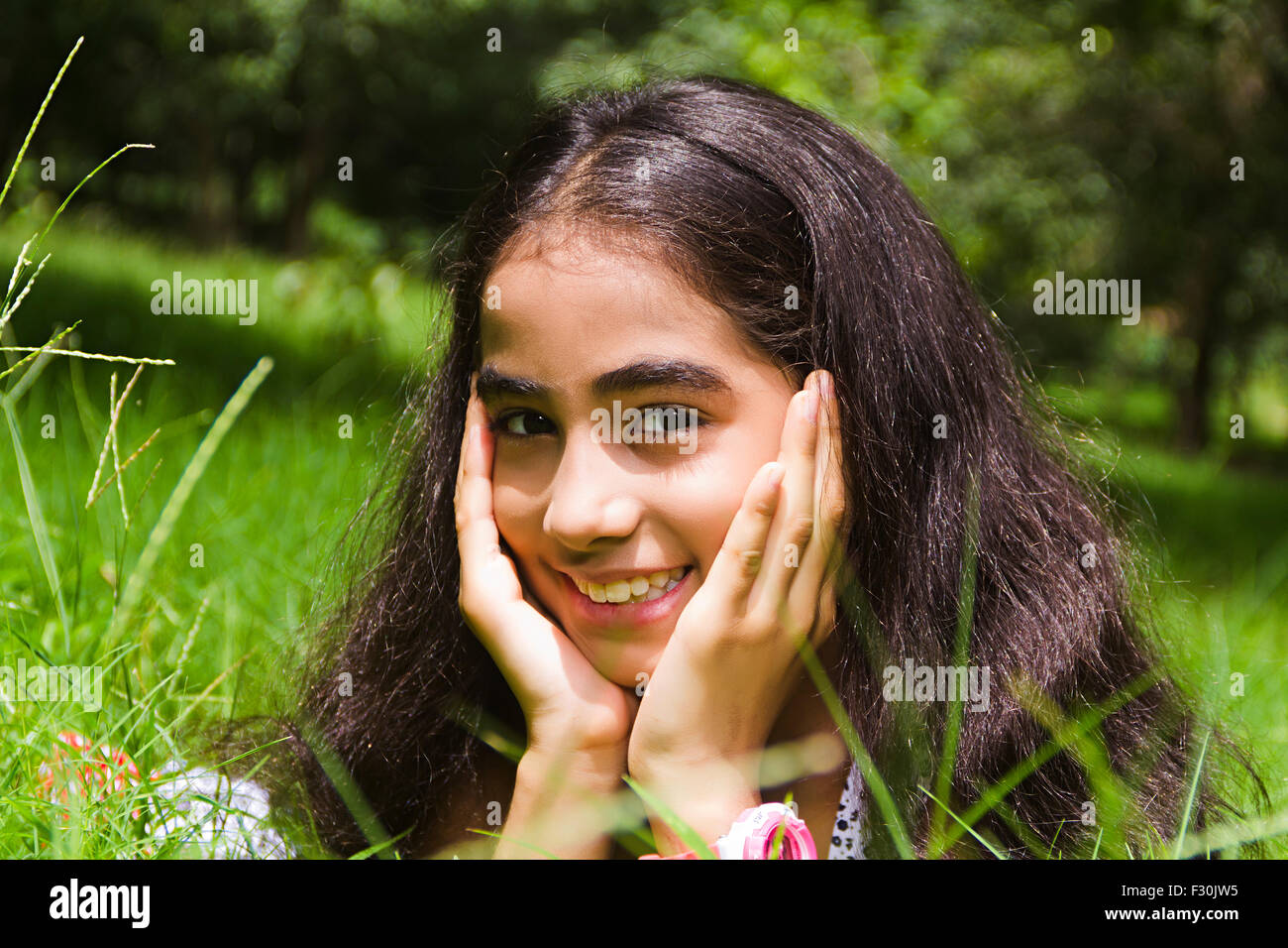 Capelli neri; nero-capelli; un abbigliamento sportivo; abiti casual; infanzia; mento sulla mano; mento sulle mani; Closeup; godendo; GIARDINAGGIO; le mani sul mento; la testa e la spalla; indulgere; innocenza; Stili di vita; un popolo; una persona; una sola persona; giocoso giocando; Gioco Foto Stock