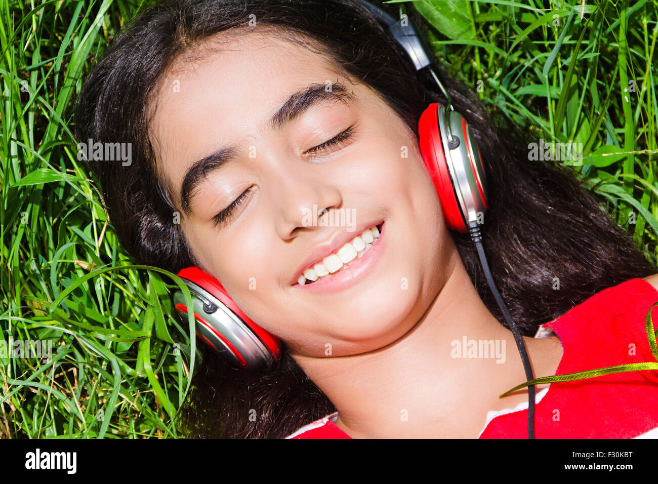 Capelli neri; nero-capelli; un abbigliamento sportivo; abiti casual; Colore immagine; destinazioni; auricolari; elettronica; esaltante; femmine; la testa e le spalle; cuffie; giacente sul retro; un popolo; una persona; una sola persona; esterni; appassionato; giocosità; se Foto Stock