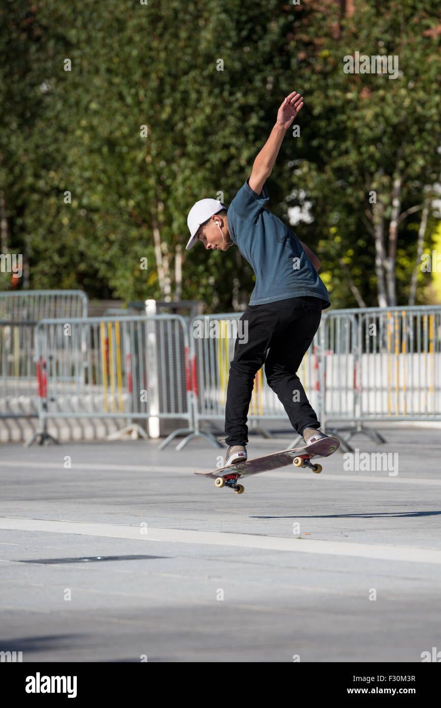 Un giovane ragazzo di eseguire trucchi sul suo skateboard in un parcheggio in Birmingham West Midlands, Regno Unito Foto Stock