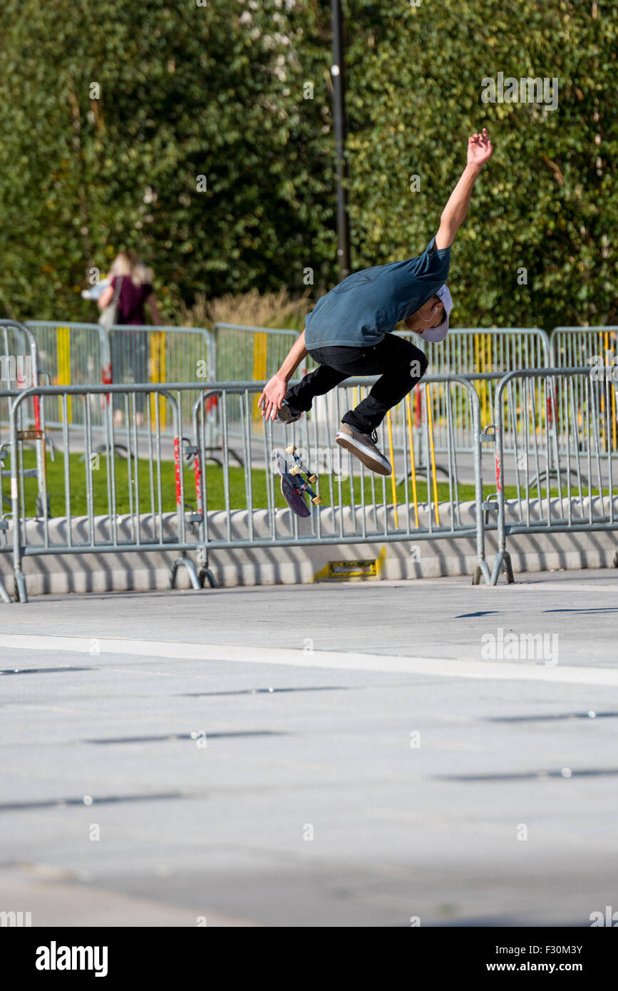 Un giovane ragazzo di eseguire trucchi sul suo skateboard in un parcheggio in Birmingham West Midlands, Regno Unito Foto Stock