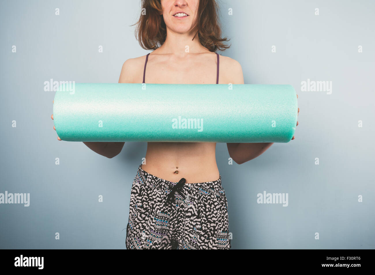 Atletica Giovane donna è in possesso di un rullo in gomma spugna per esercizio Foto Stock