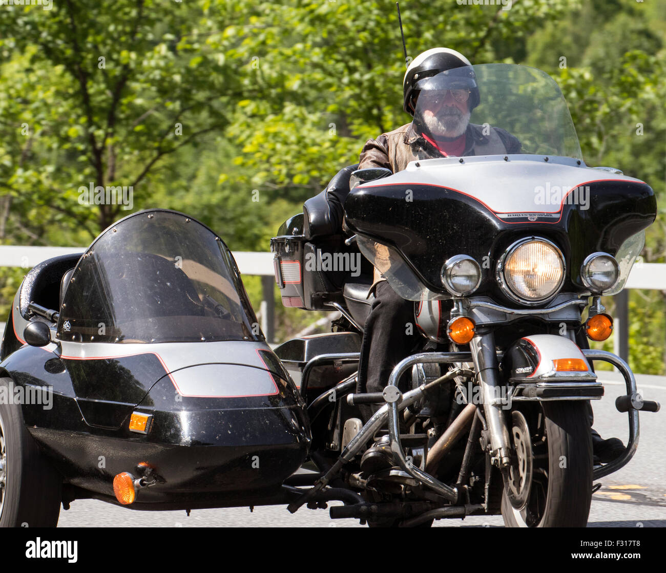 Uomo su una Harley Davidson moto motociclo con sidecar corrispondente lato auto. Foto Stock