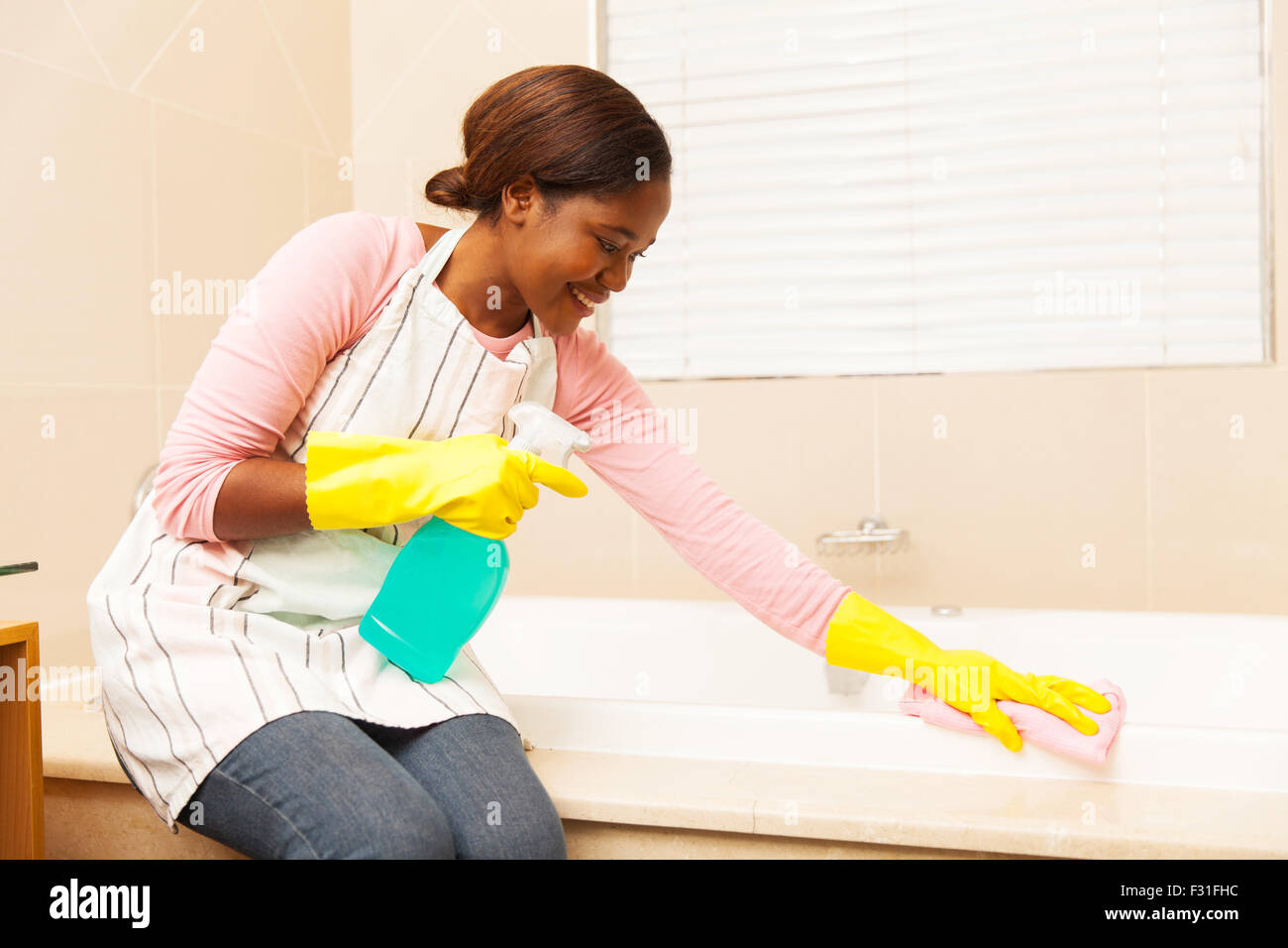 Pretty African casalinga pulizia vasca da bagno a casa Foto stock - Alamy