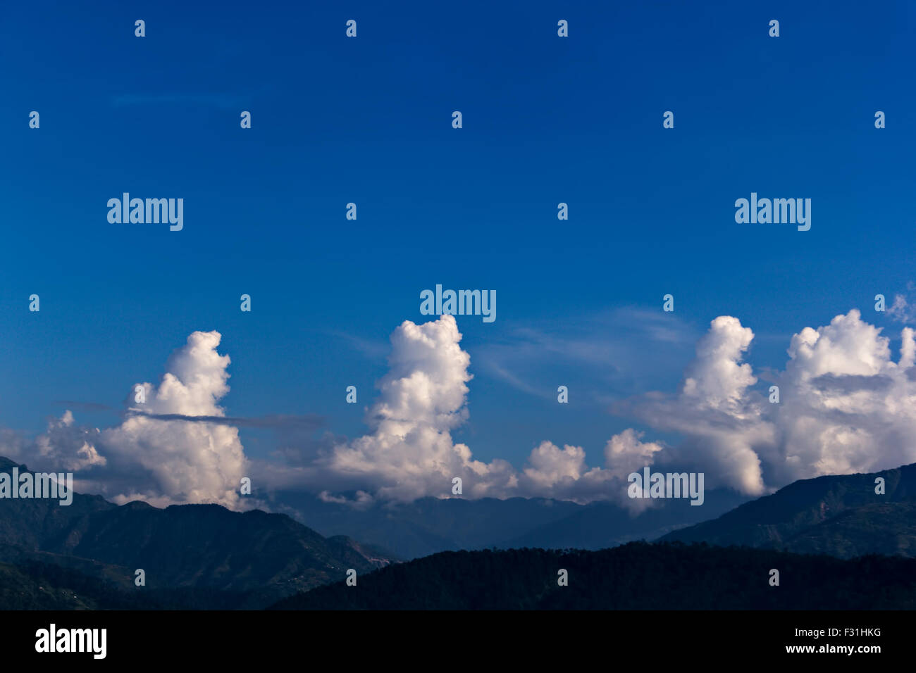 Puffy bianche nuvole sollevando da una montagna Foto Stock