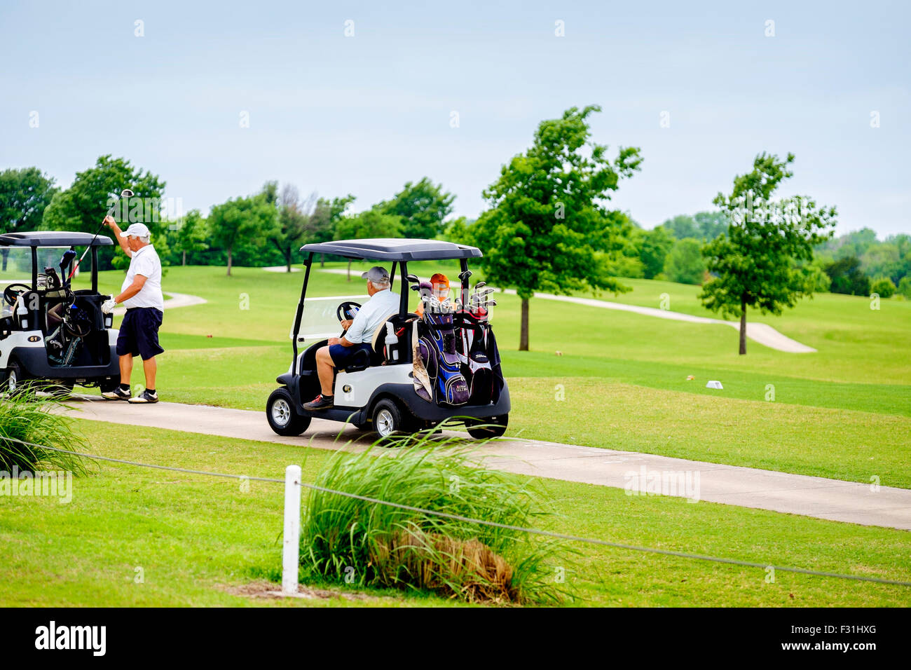 Gli uomini ride in carrelli da golf su un percorso per carrello durante un torneo a Hefner Campo da golf nella città di Oklahoma, Oklahoma, Stati Uniti d'America. Foto Stock