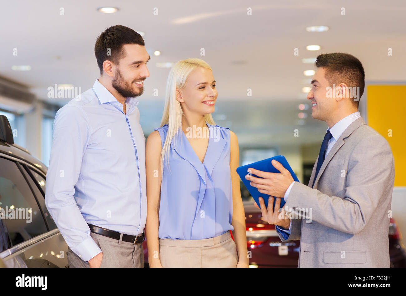 Coppia felice con il rivenditore di auto in auto show o salon Foto Stock