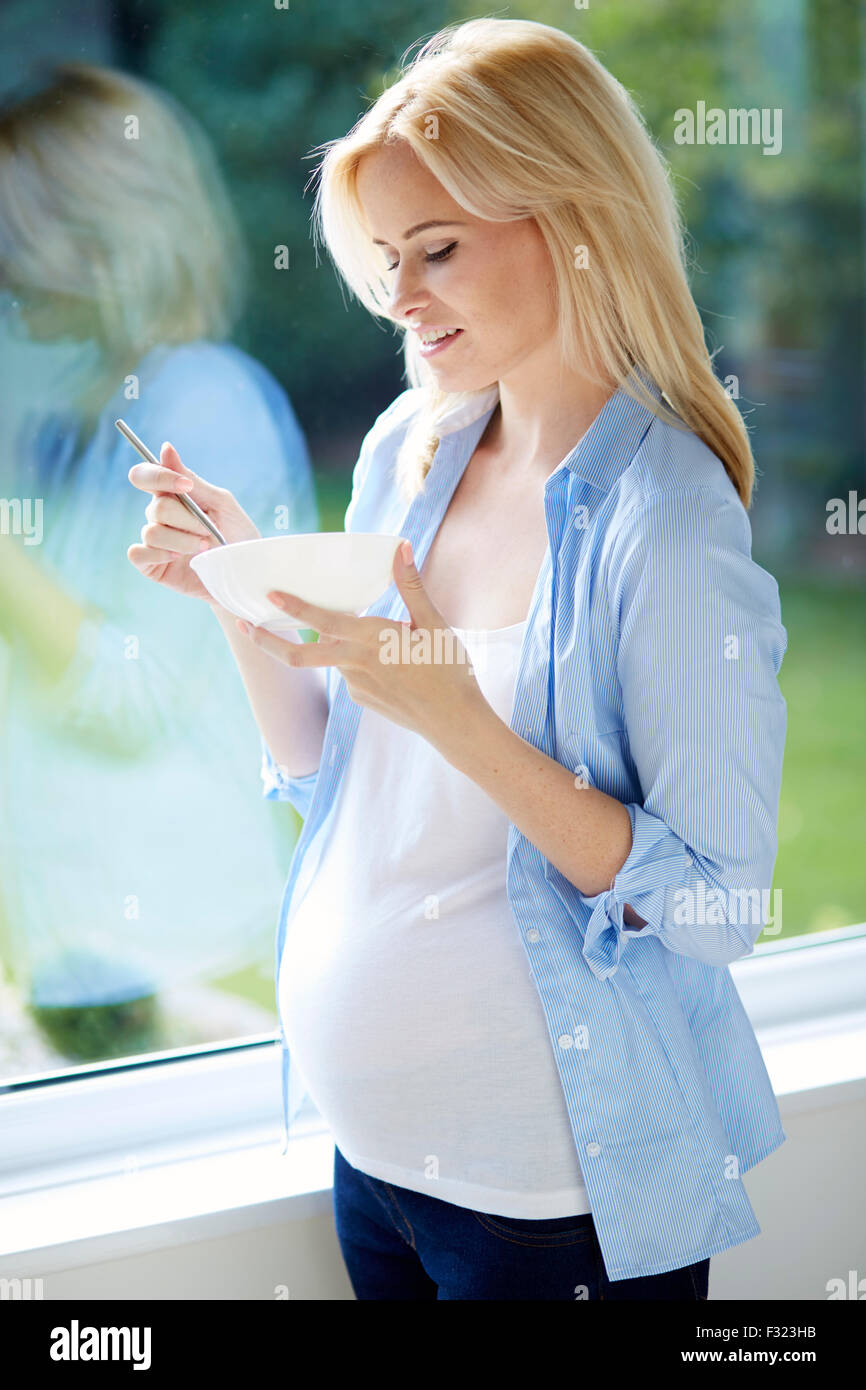 Donna incinta 30 settimane mangiare cereali per la prima colazione Foto Stock