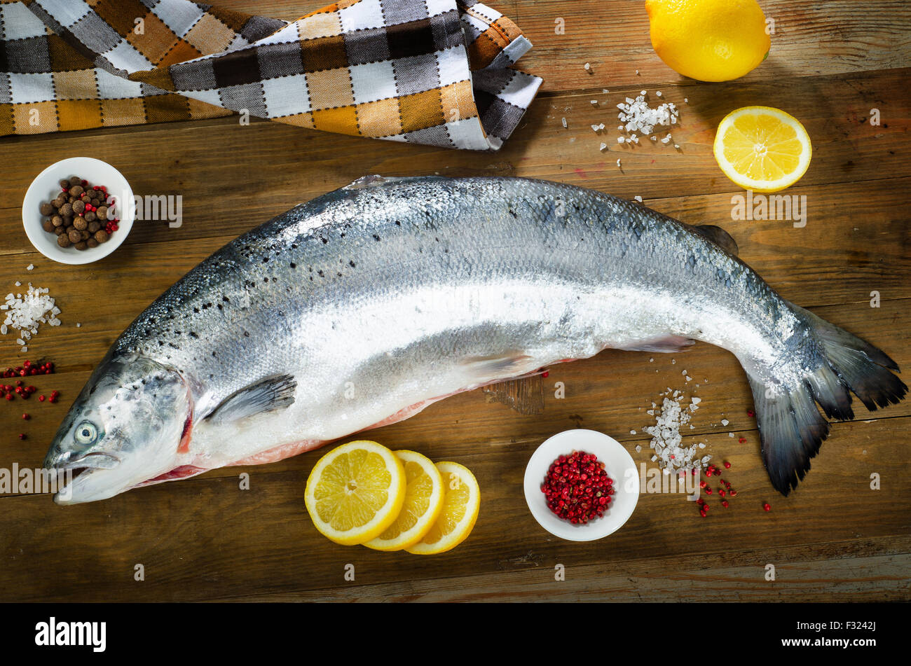 Pesce fresco di un tavolo di legno con sale e fettine di limone Foto Stock