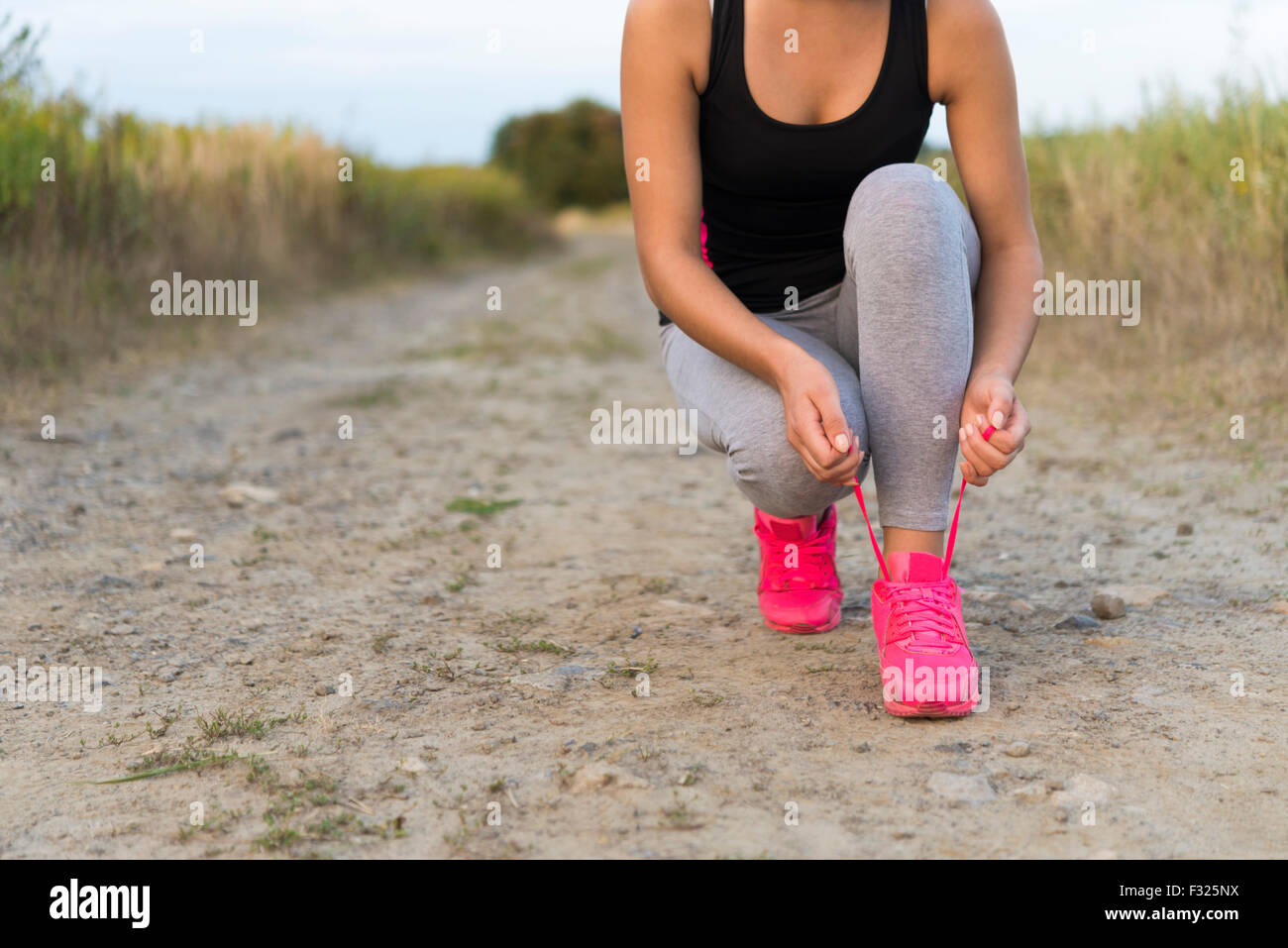 Lo sport femminile fitness runner scarpe di legatura e tenetevi pronti per il jogging sulla strada di campagna Foto Stock