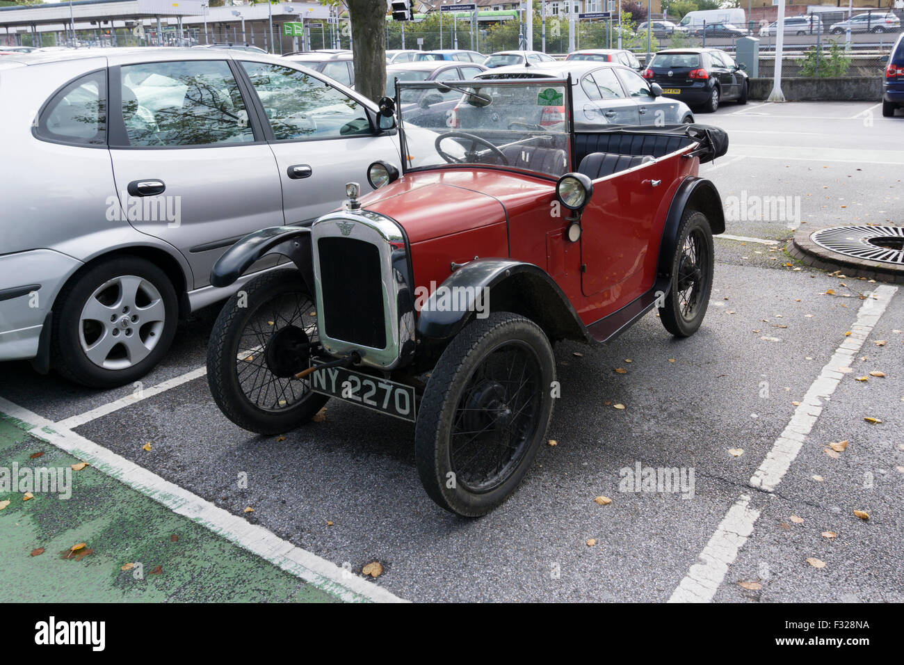 Un piccolo vintage 7 Austin auto in un parcheggio con più grande salone moderno vetture. Foto Stock