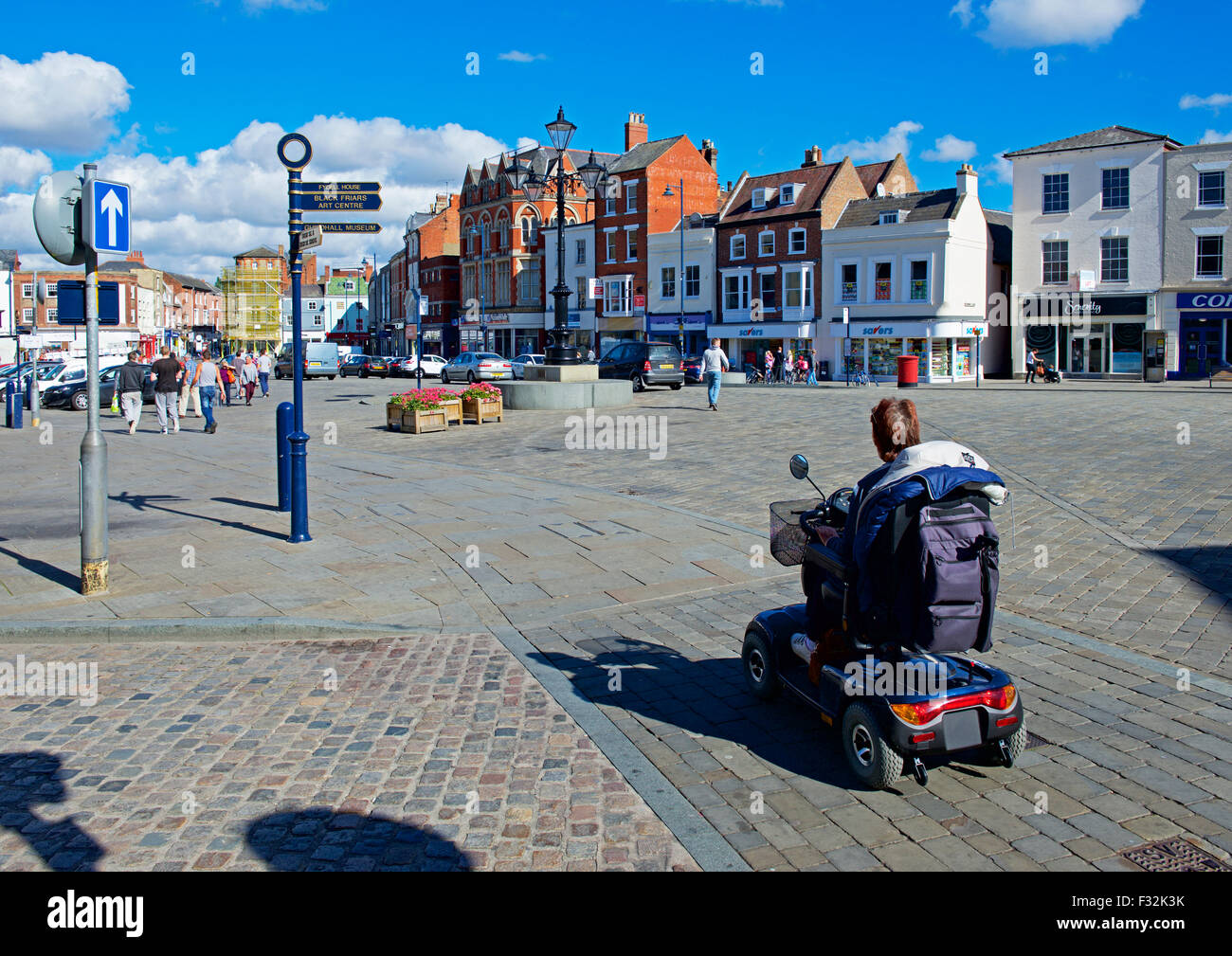 Donna sulla mobilità scooter in piazza del mercato, Boston, Lincolnshire, England Regno Unito Foto Stock