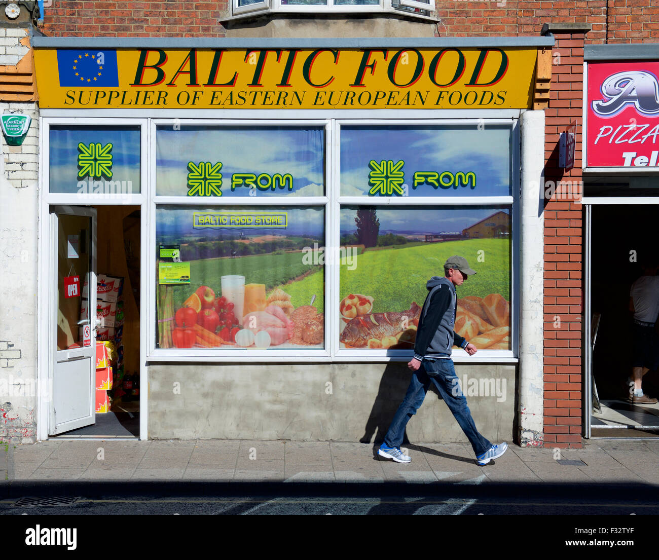 Giovane uomo a camminare passato negozio di vendita East cibo europeo di Boston, Lincolnshire, England Regno Unito Foto Stock