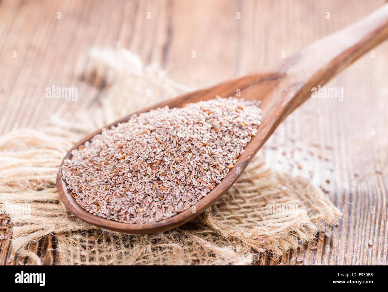 Il cucchiaio di legno con semi di psillio su sfondo scuro Foto Stock