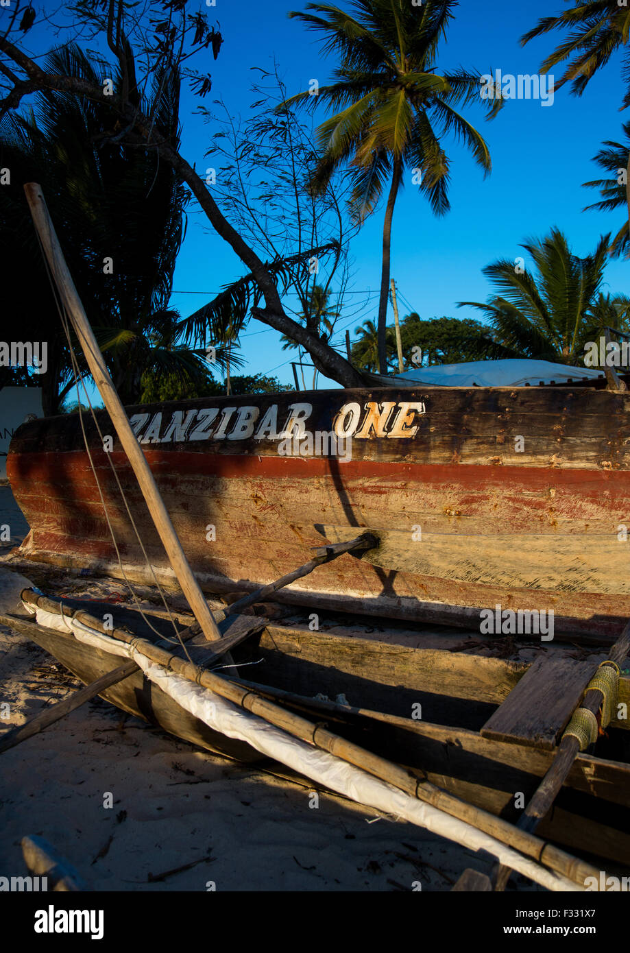 Tanzania, Zanzibar, Kizimkazi, un vecchio legno dhow pesca in appoggio su di una spiaggia di sabbia tra alberi di palma Foto Stock