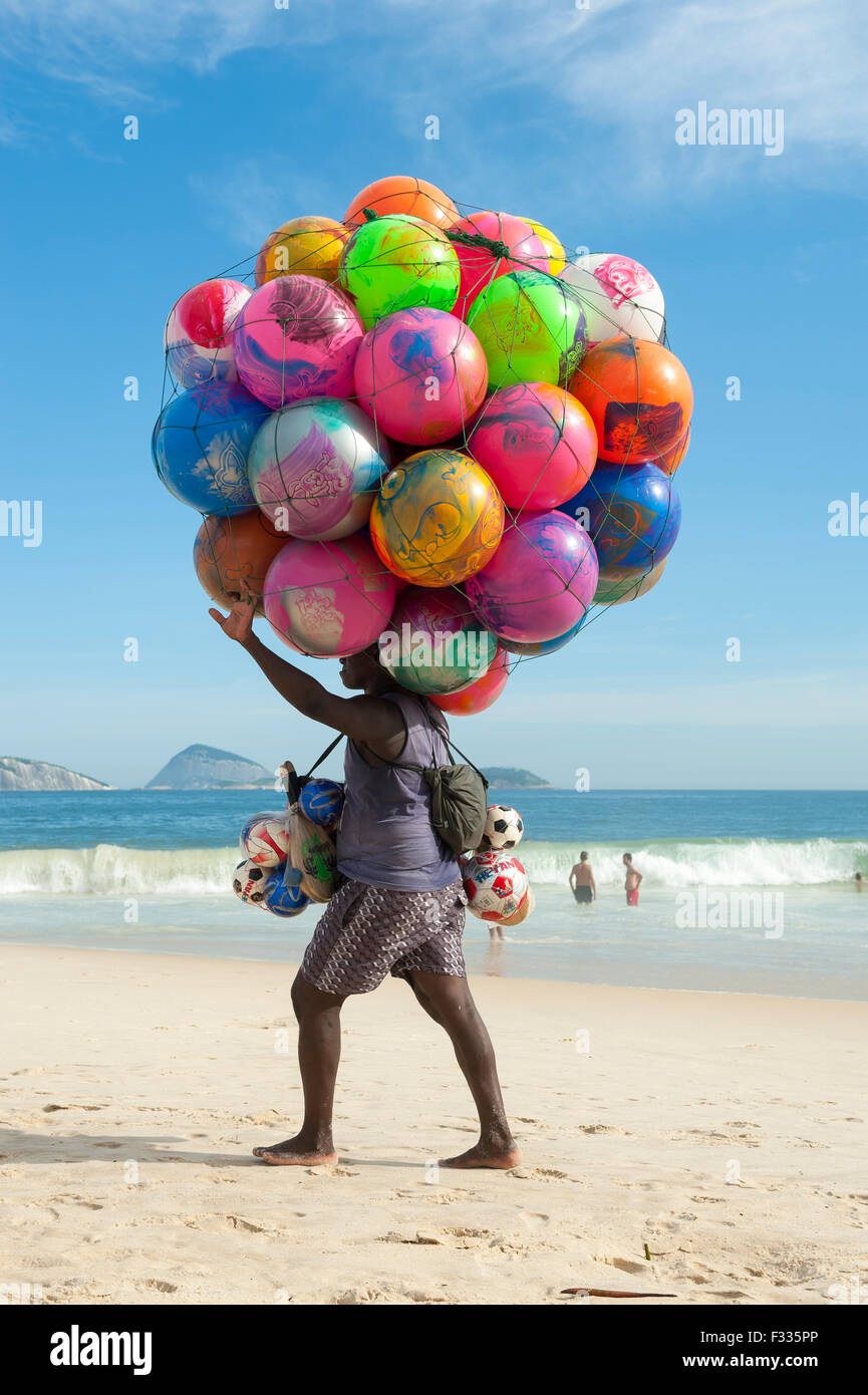 RIO DE JANEIRO, Brasile - 20 gennaio 2013: Spiaggia venditore a vendere pittoresca spiaggia di sfere porta la sua merce lungo la spiaggia di Ipanema Foto Stock