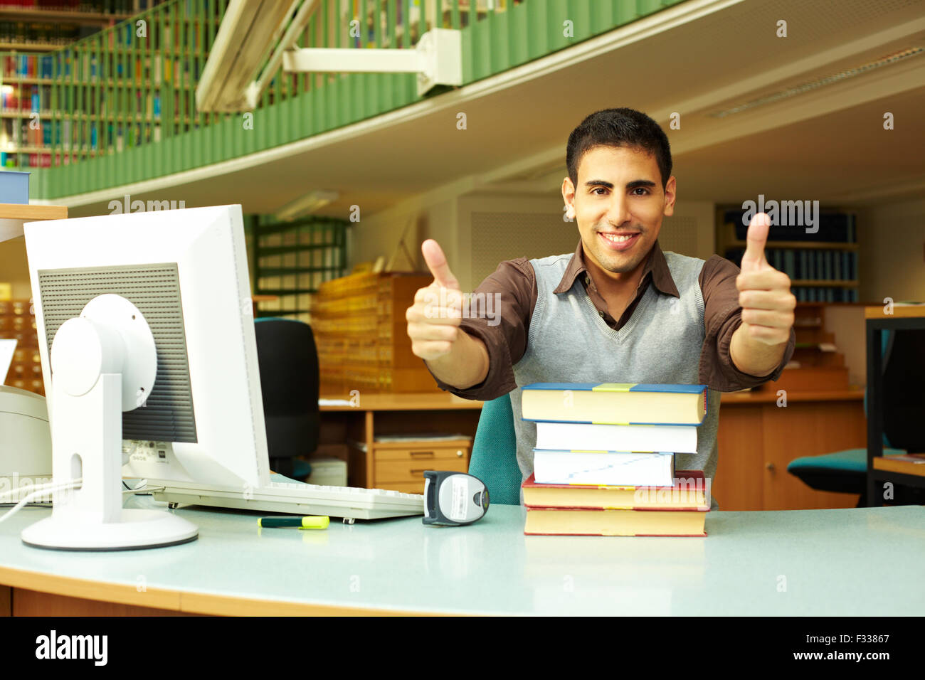 Felice bibliotecario al desk tenendo il suo pollice in alto Foto Stock