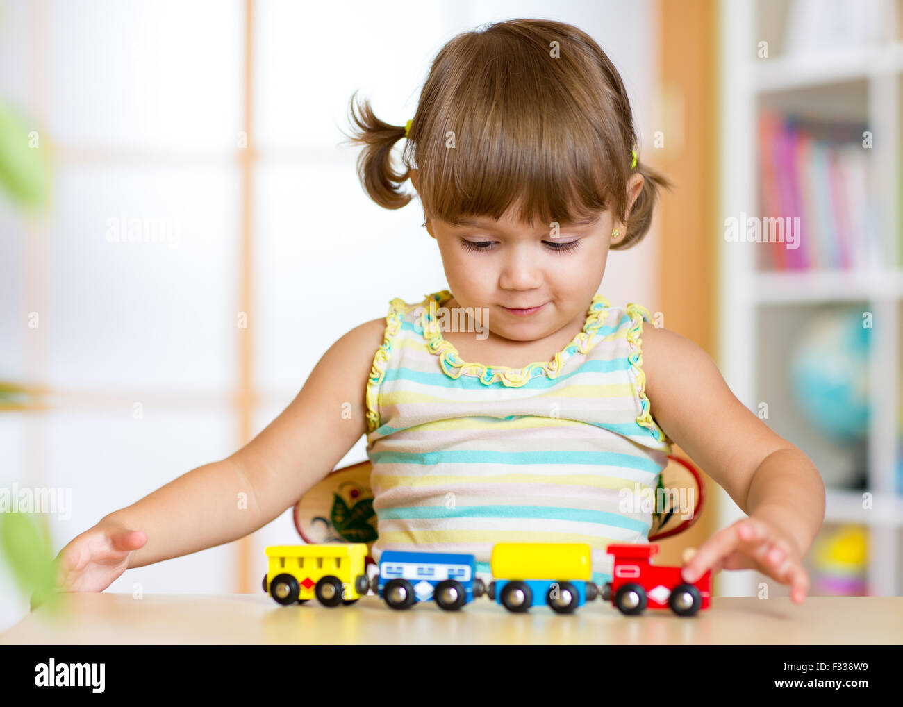 Carino kid girl riproduzione di treni di legno toy Foto Stock