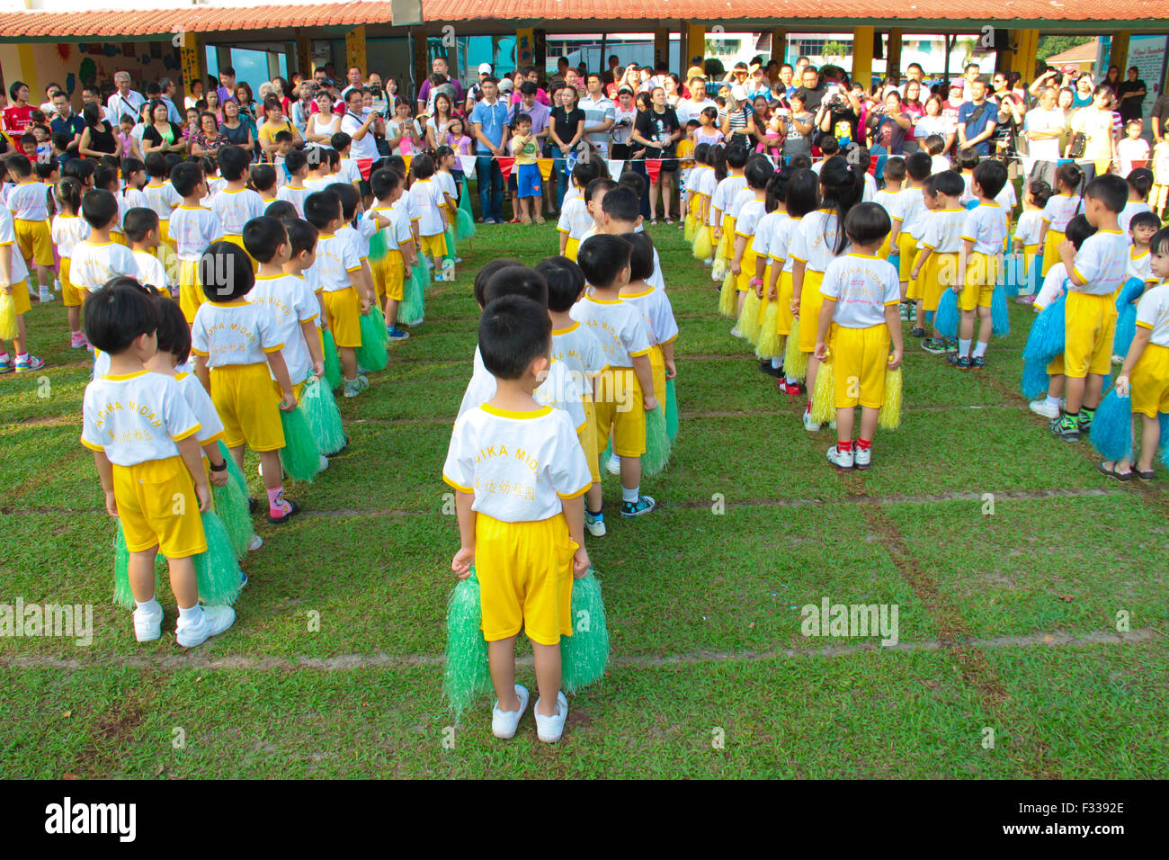 Kindergarten bambini line up e tenendo pompon davanti la loro anticipando i genitori durante la loro giornata di sport. Foto Stock